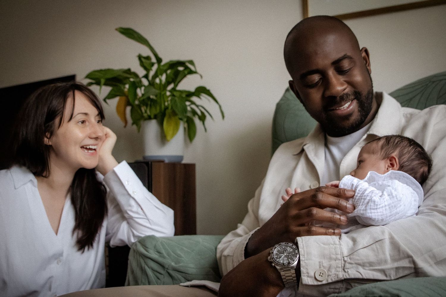 Family sharing tender moments with newborn on couch.