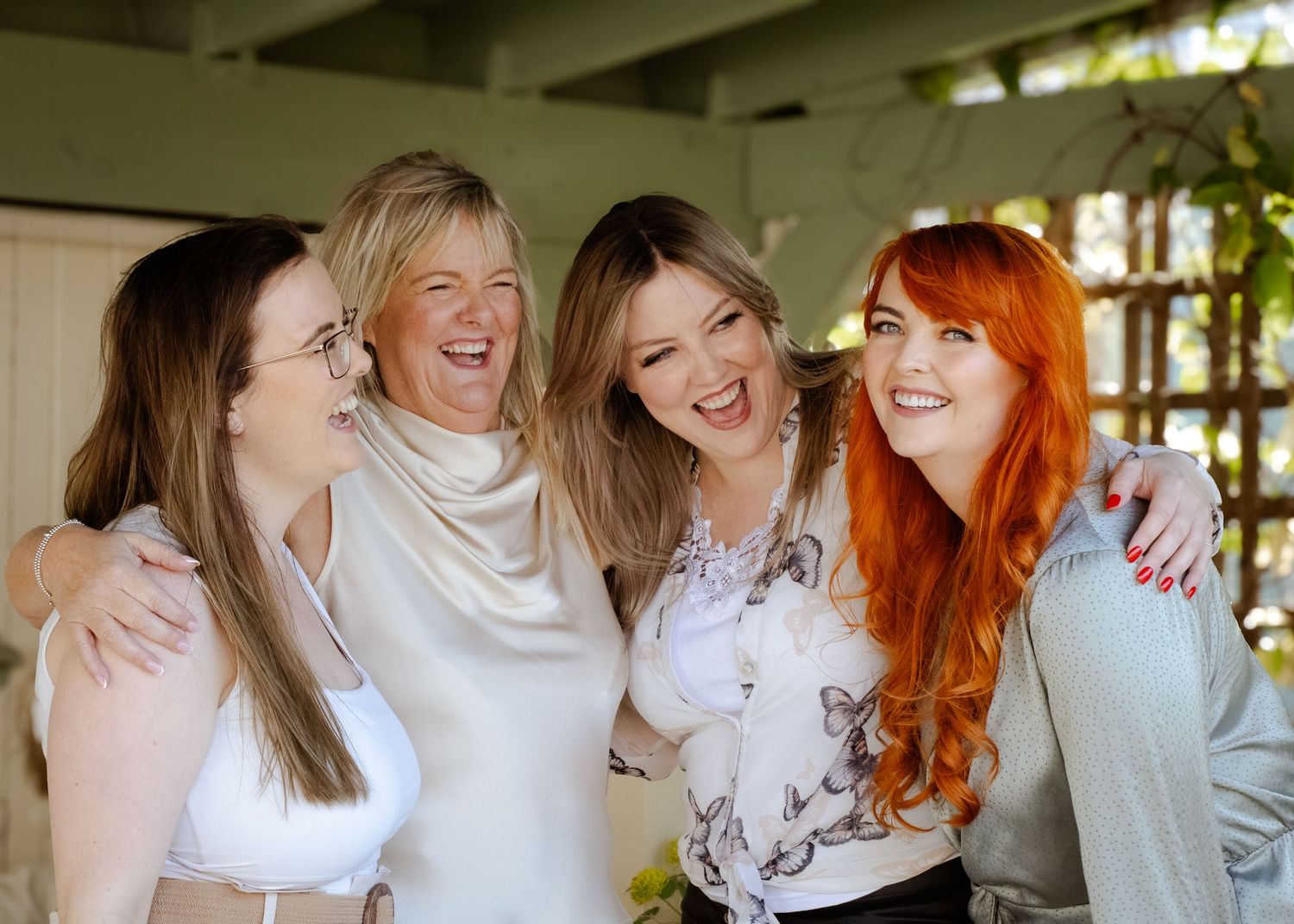 Group of friends in white tops laughing and hugging together in casual setting.