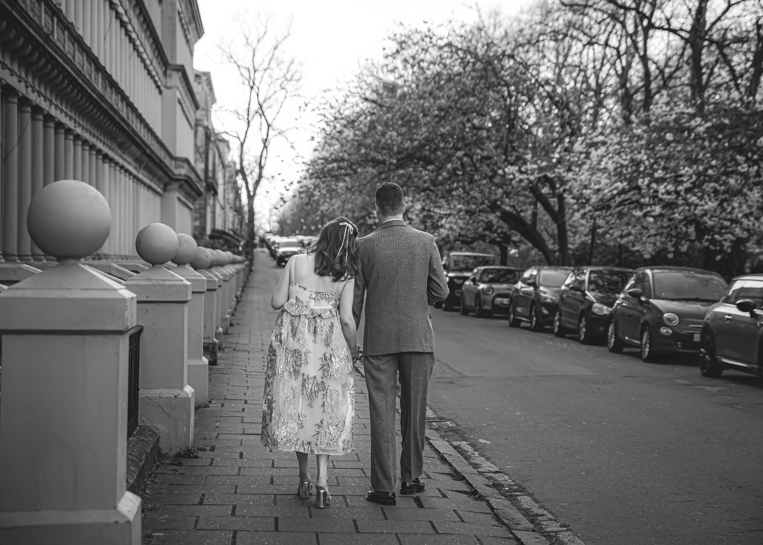 Black and white street photography sequence of couple walking along historic buildings.