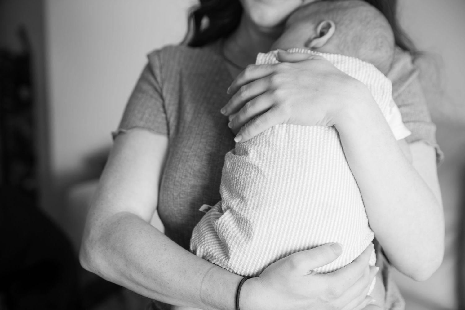 Black and white series showing tender moments with infant in white clothing.