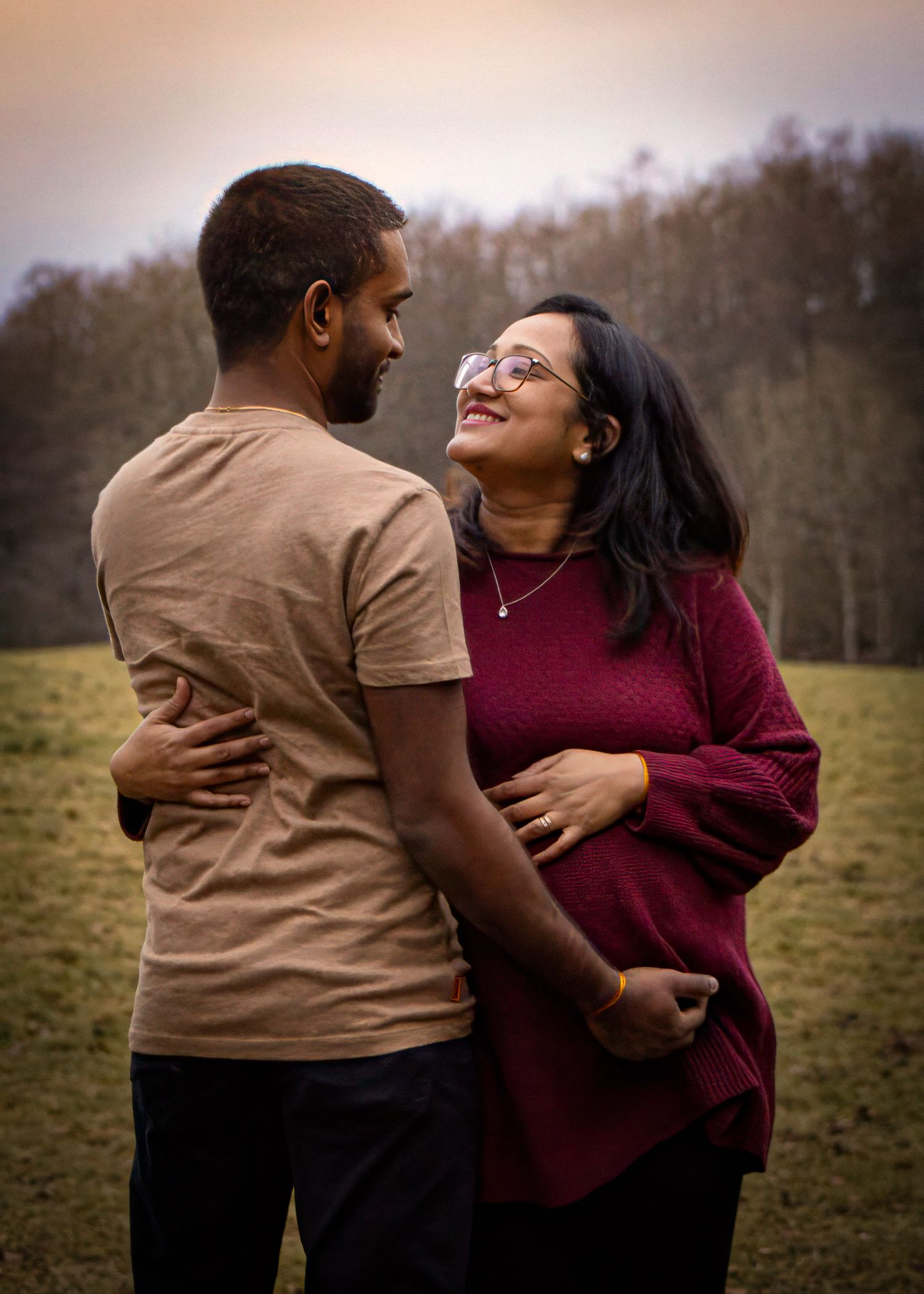 Romantic couple embracing in field during golden hour.