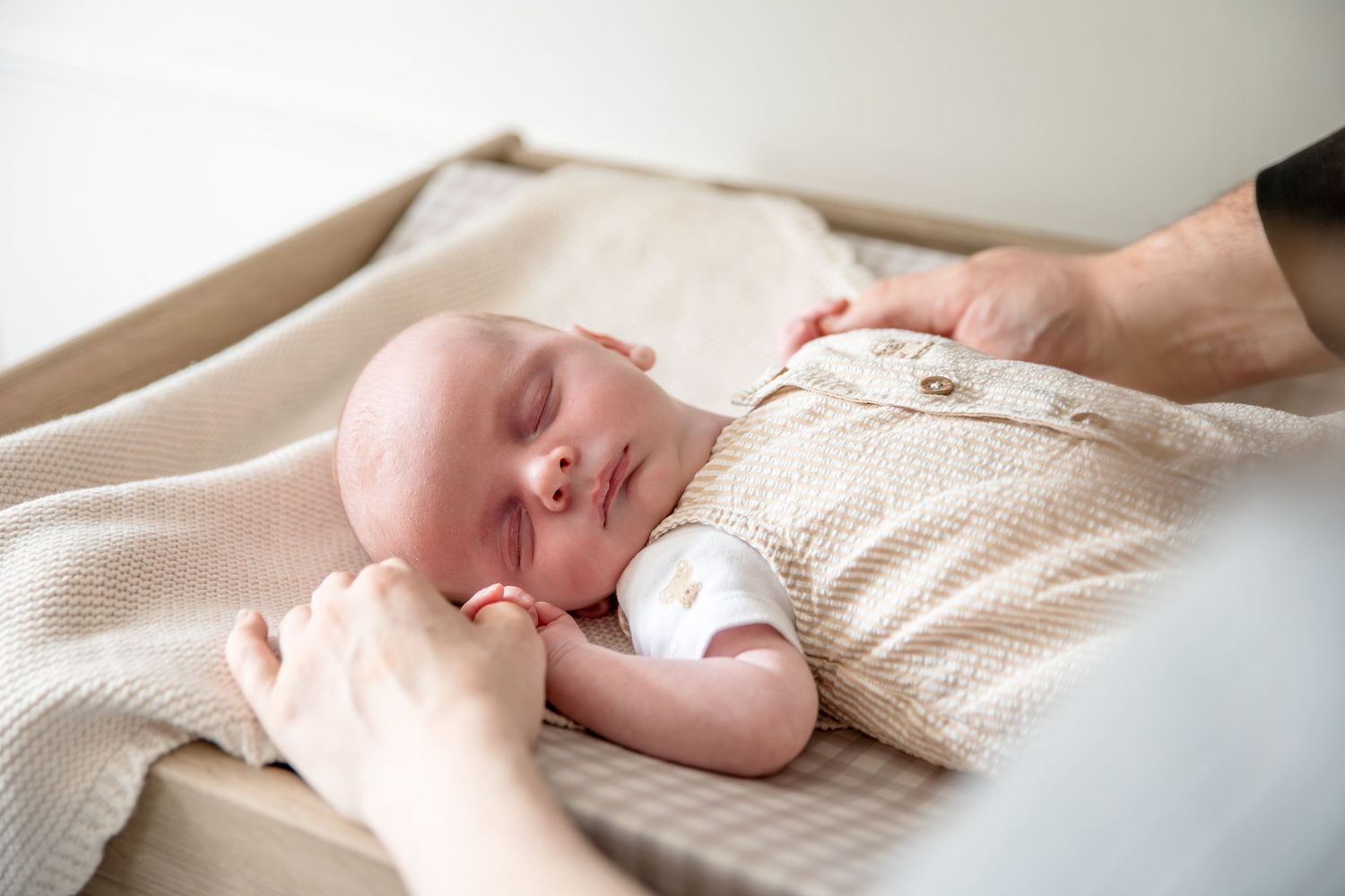Close up of sleeping newborn on textured cream blanket.