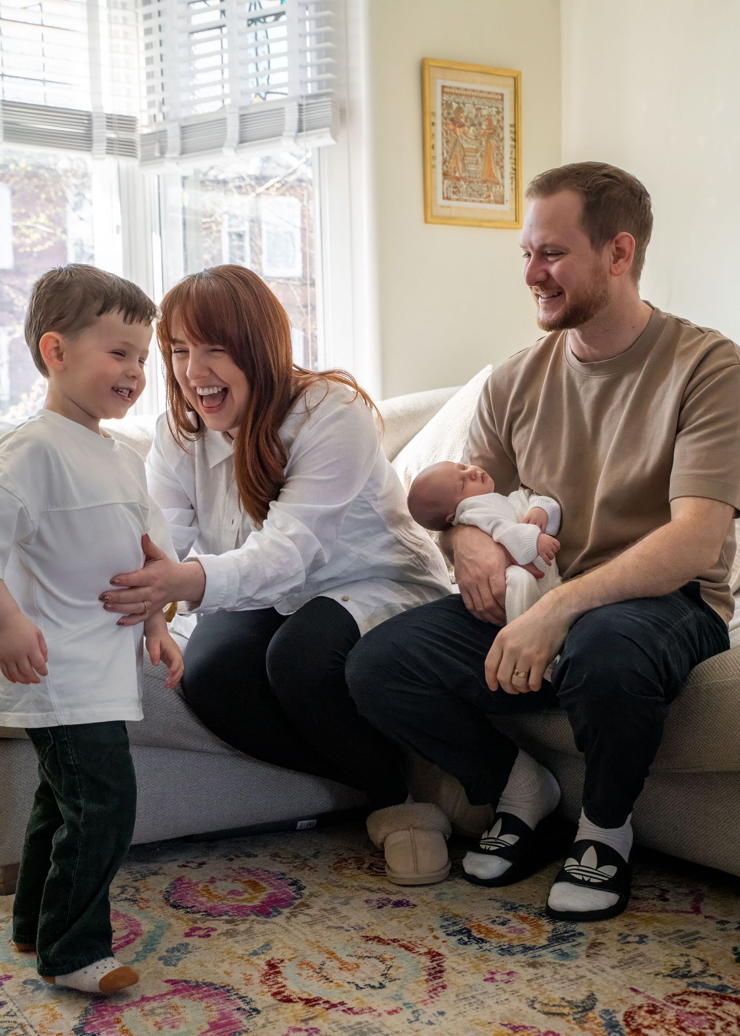 Family sharing joyful moments on colorful rug in sunlit room.