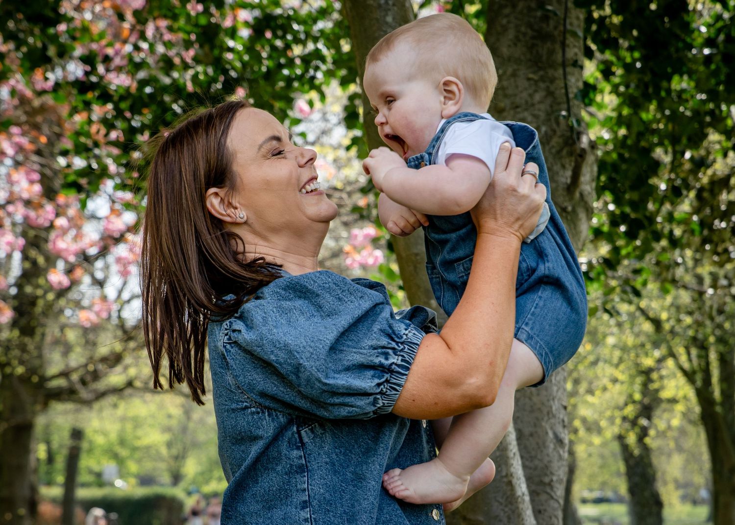 A joyful outdoor moment shared between parent and child among blooming trees.