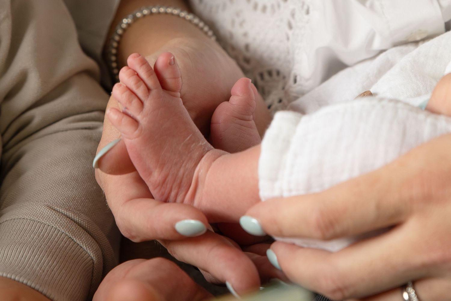 Close-up of baby feet being gently held by adult hands.