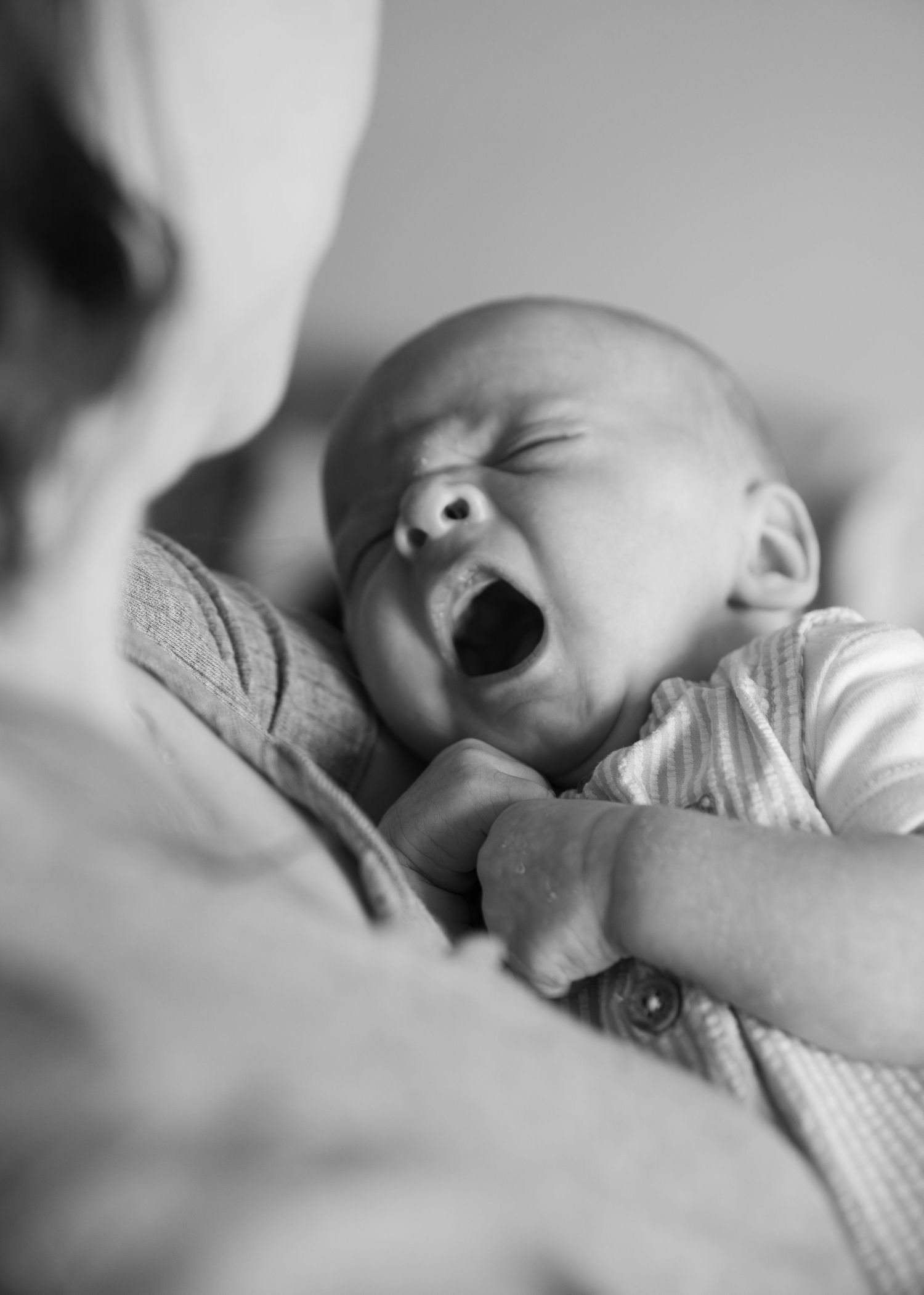 Black and white portrait of a sleeping newborn baby wrapped in soft blankets.