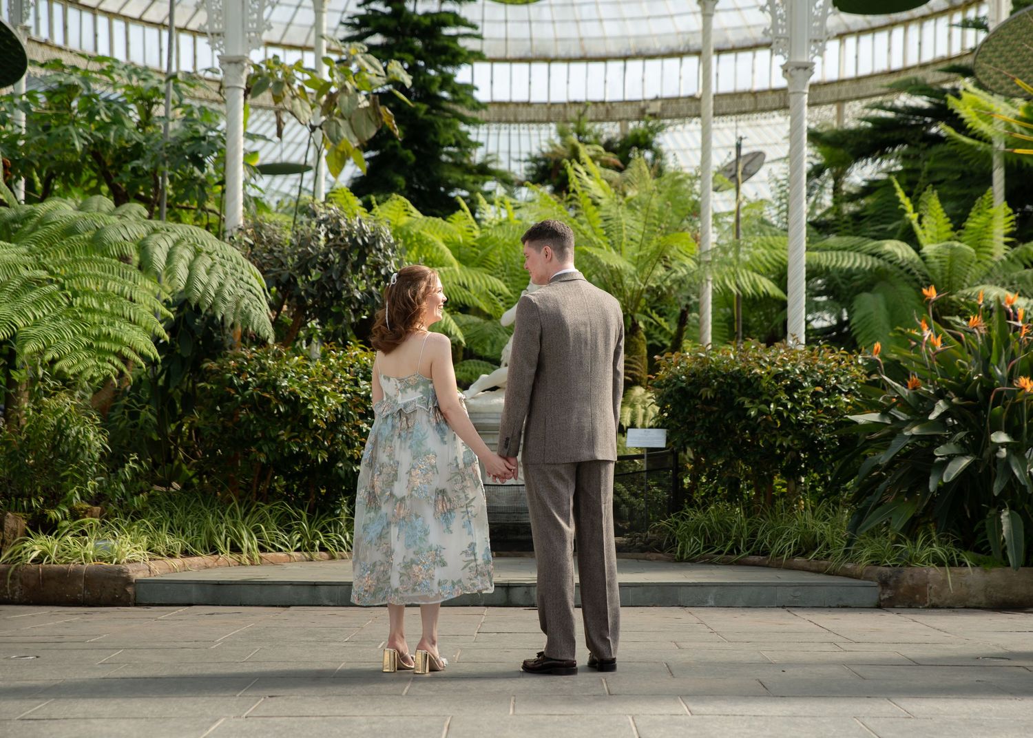 Romantic couple standing together in a beautiful greenhouse surrounded by tropical plants.