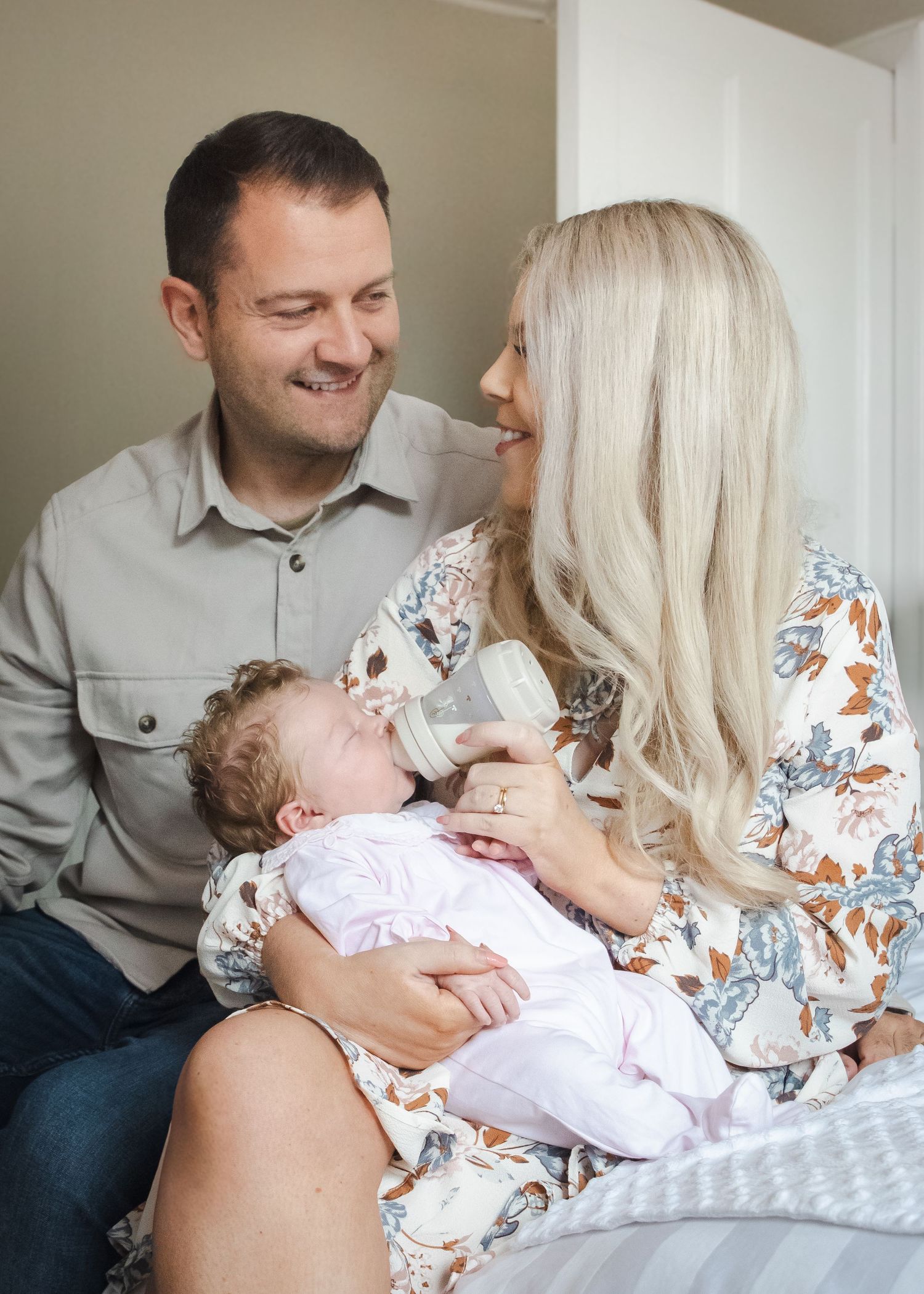 Family sharing a tender moment while bottle feeding their baby at home.