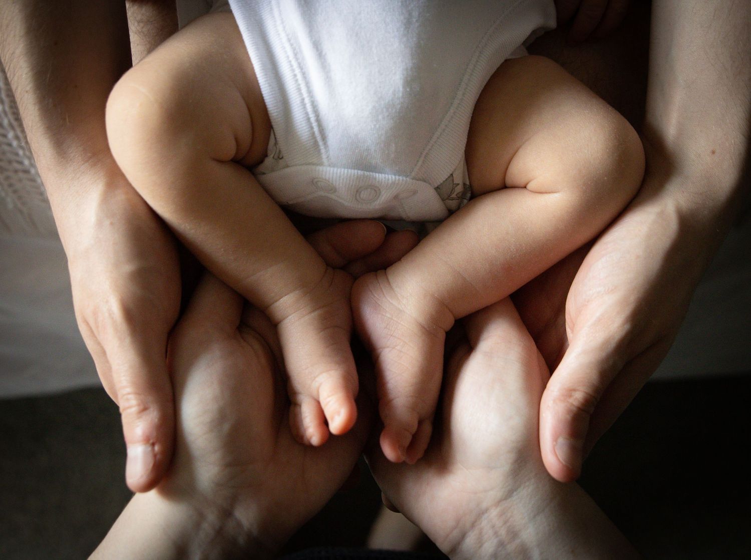 Close up series of baby feet and adult hands in intimate black and white photography.