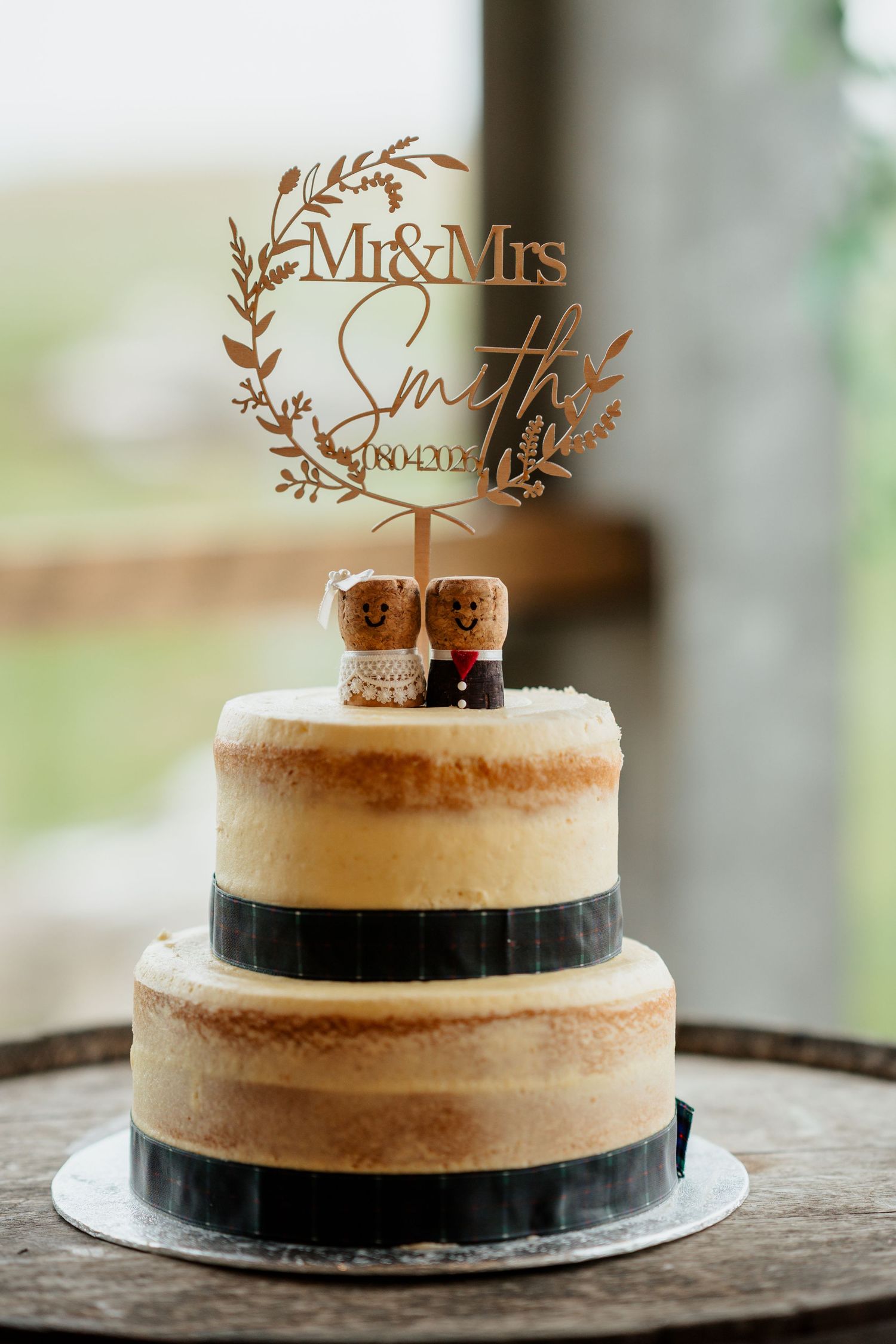 Two-tier naked wedding cake with cork figurine toppers and wooden Mr & Mrs Smith laser cut cake topper.