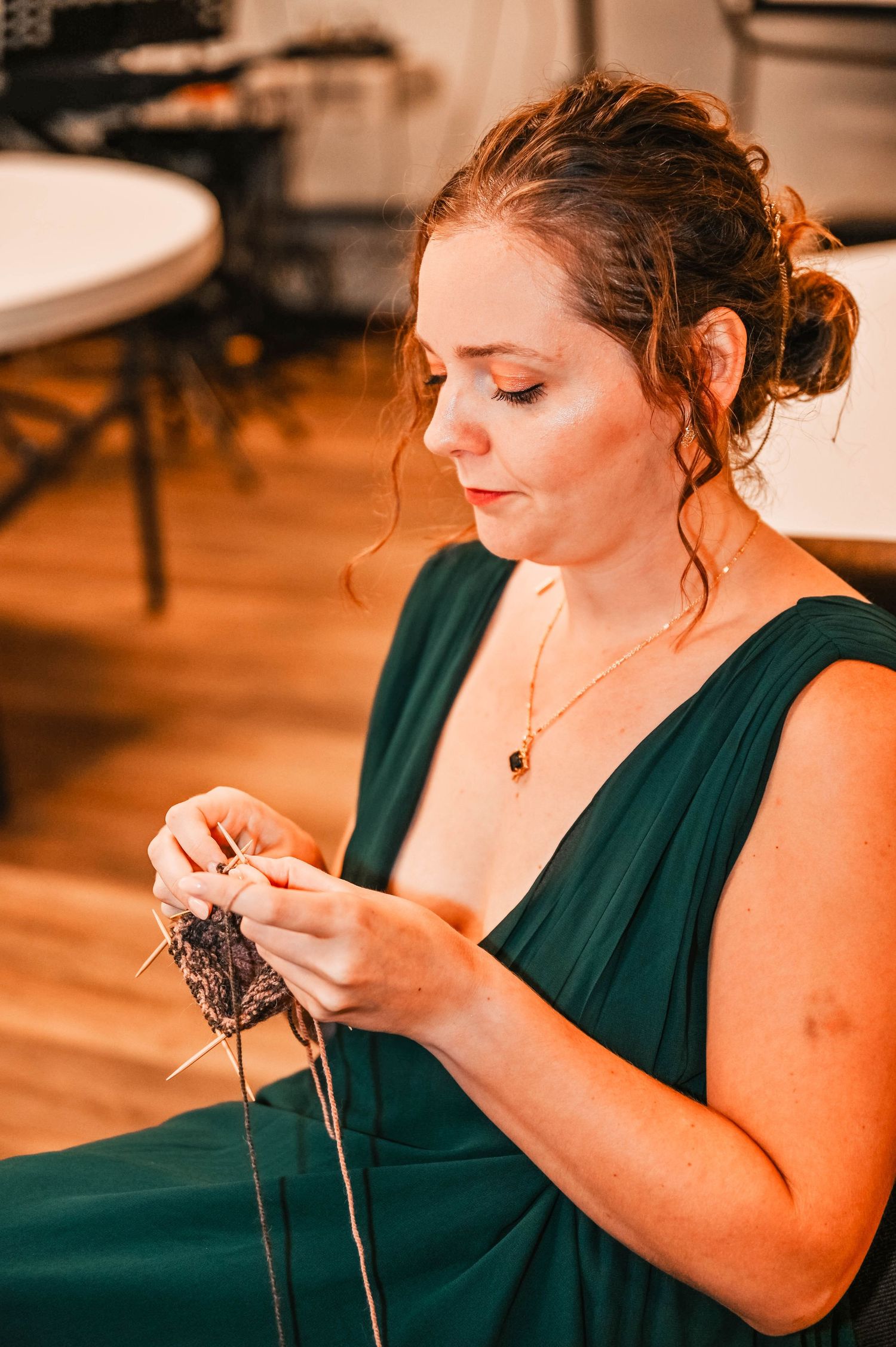 Person in dark green dress working on detailed handcraft project.
