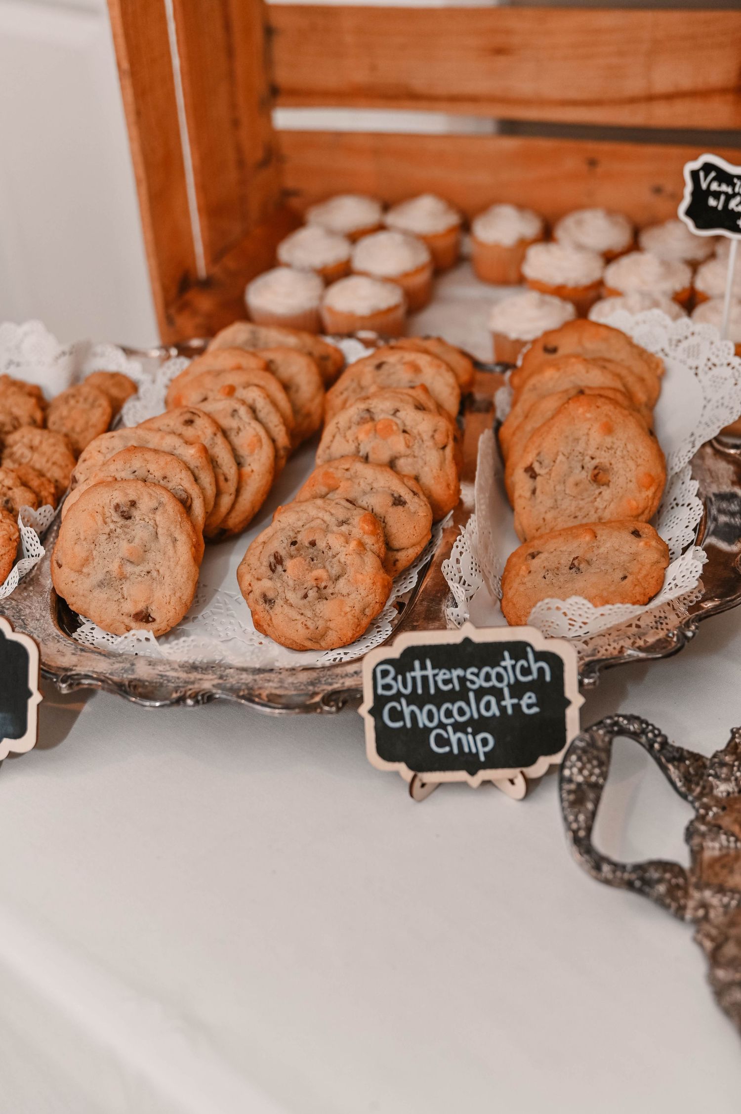Chocolate chip and butterscotch cookies arranged on doilies with chalkboard labels.