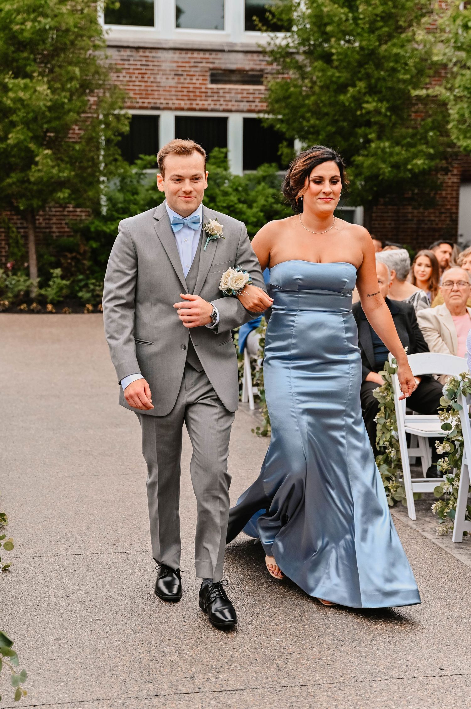 Wedding party members walk and pose playfully on a concrete patio.