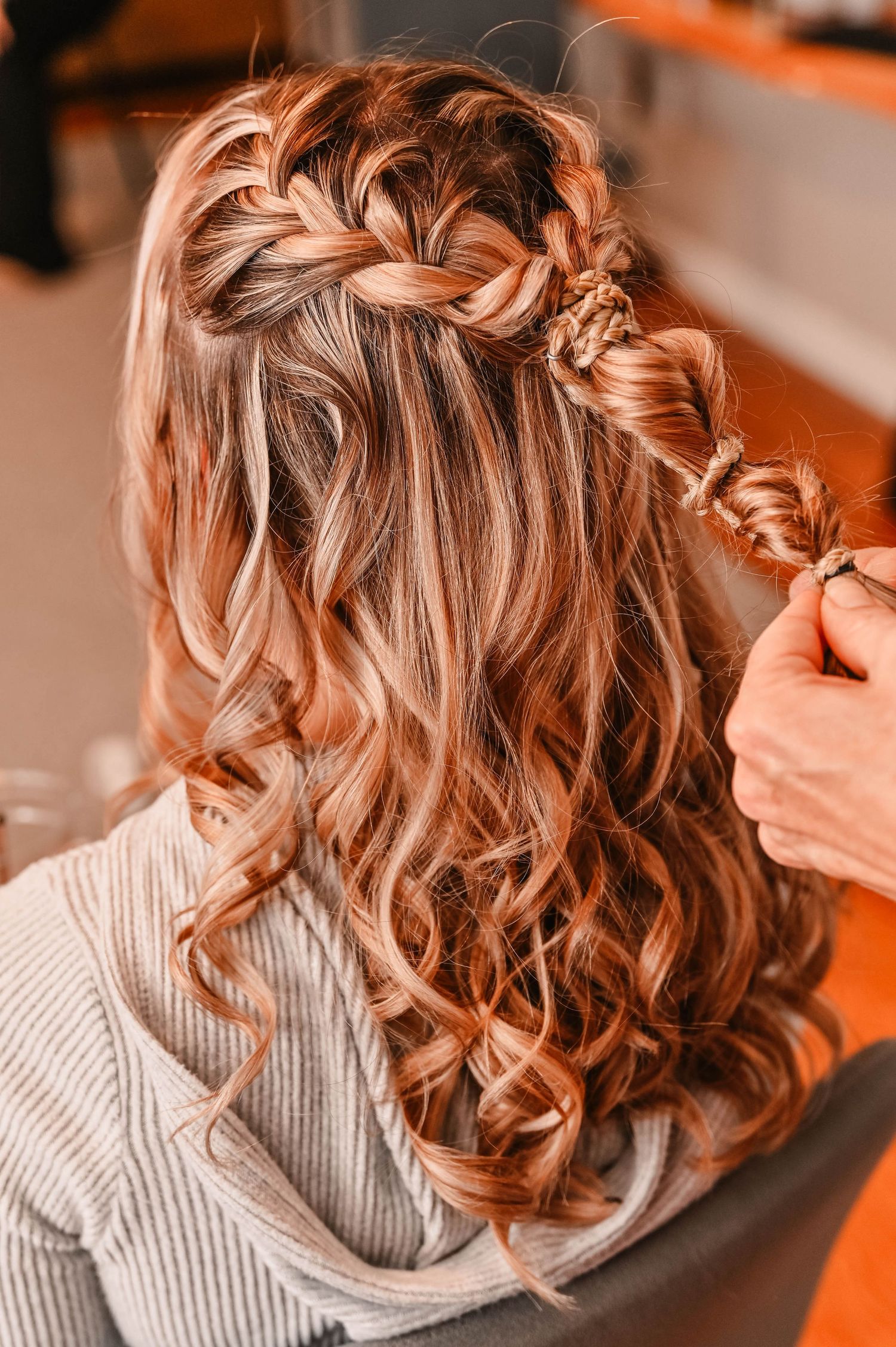 Intricate braided hairstyle with loose curls being styled for a special occasion.