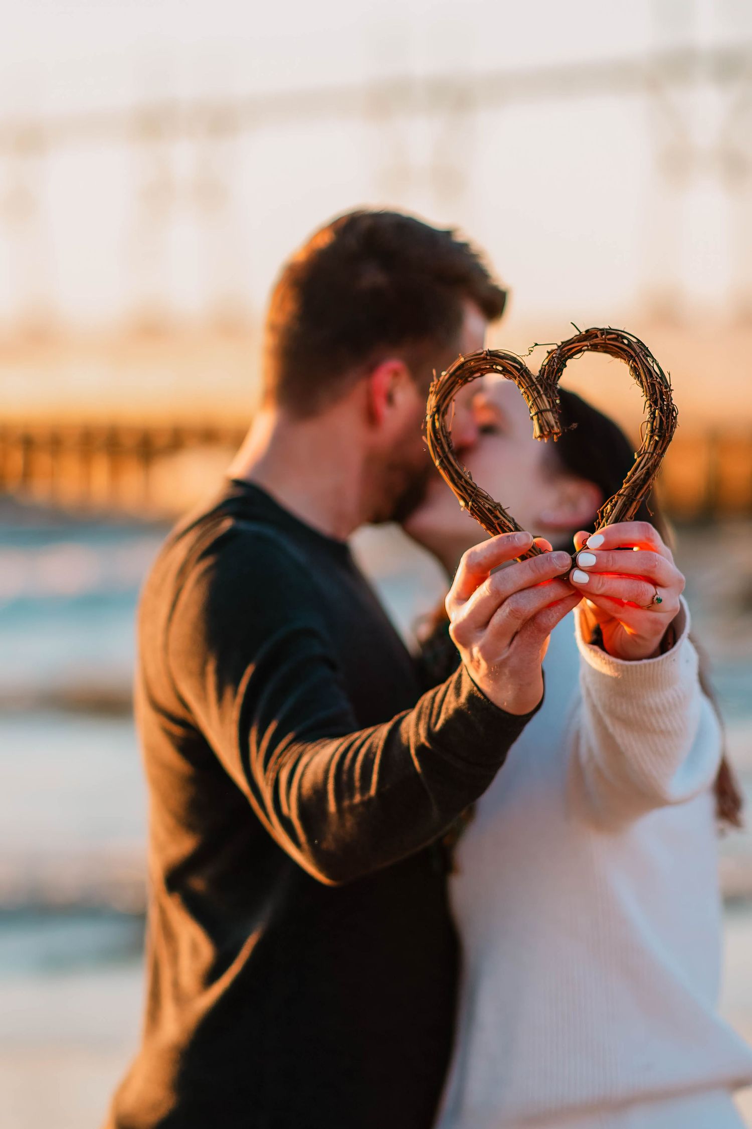 Couple sharing a pretzel in a series of romantic poses during golden hour.