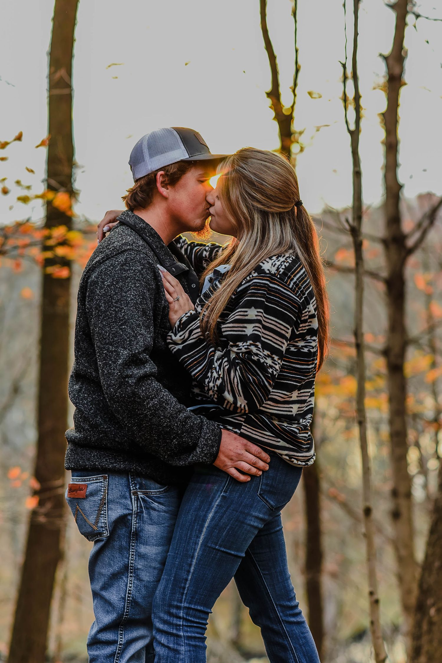 Couple embracing among autumn trees during a fall engagement photoshoot.