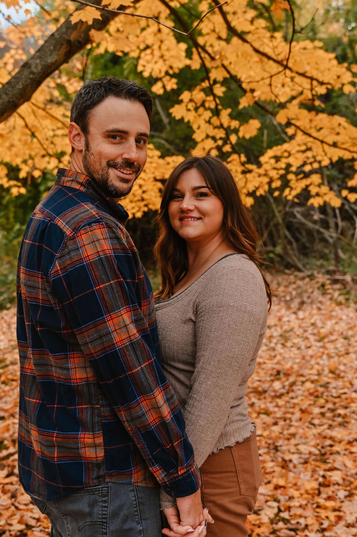 Couple sharing tender moments during fall photo session with golden foliage.