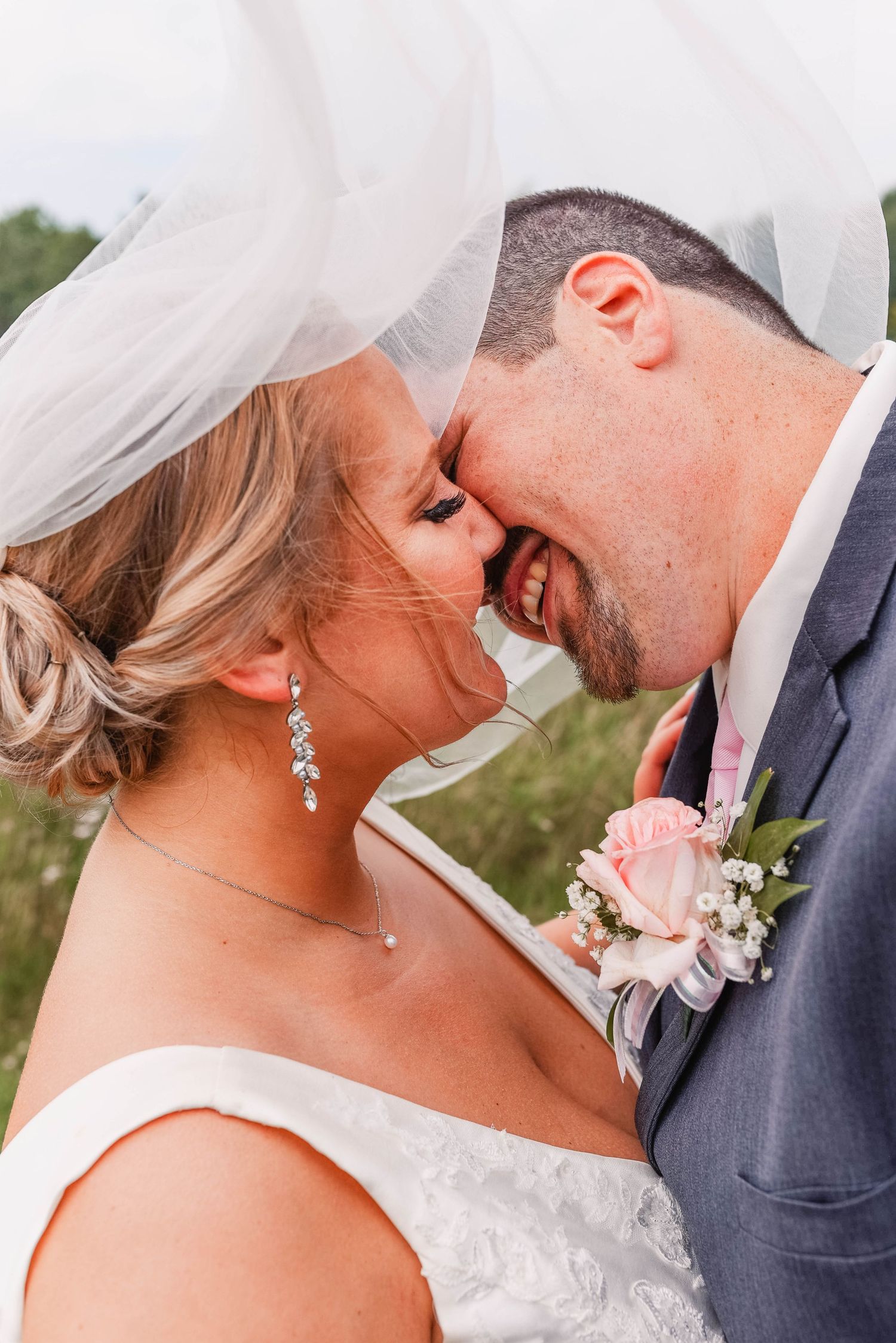 Romantic wedding couple shares intimate moments under a flowing veil.