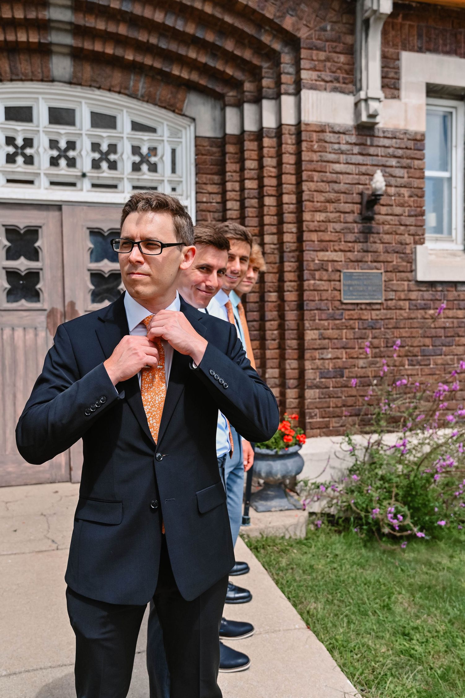 Casual group photos taken outside brick church with decorative windows.