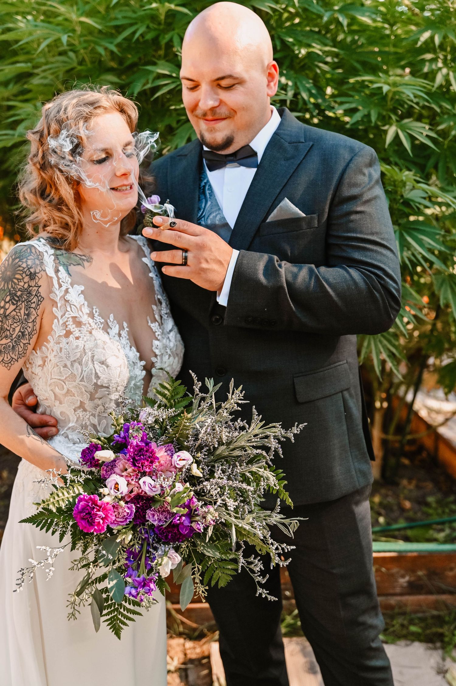 Wedding couple sharing a playful moment with purple floral bouquet in garden setting.