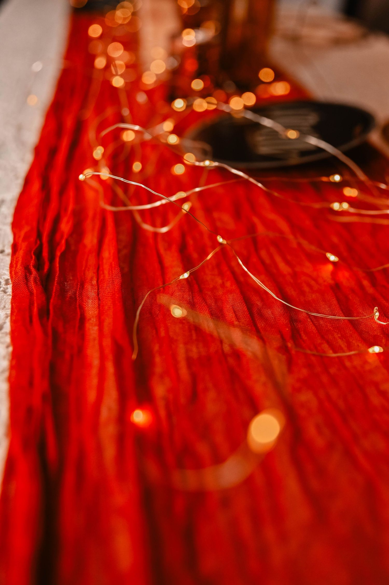 Red fabric with delicate string lights creating romantic bokeh effect.