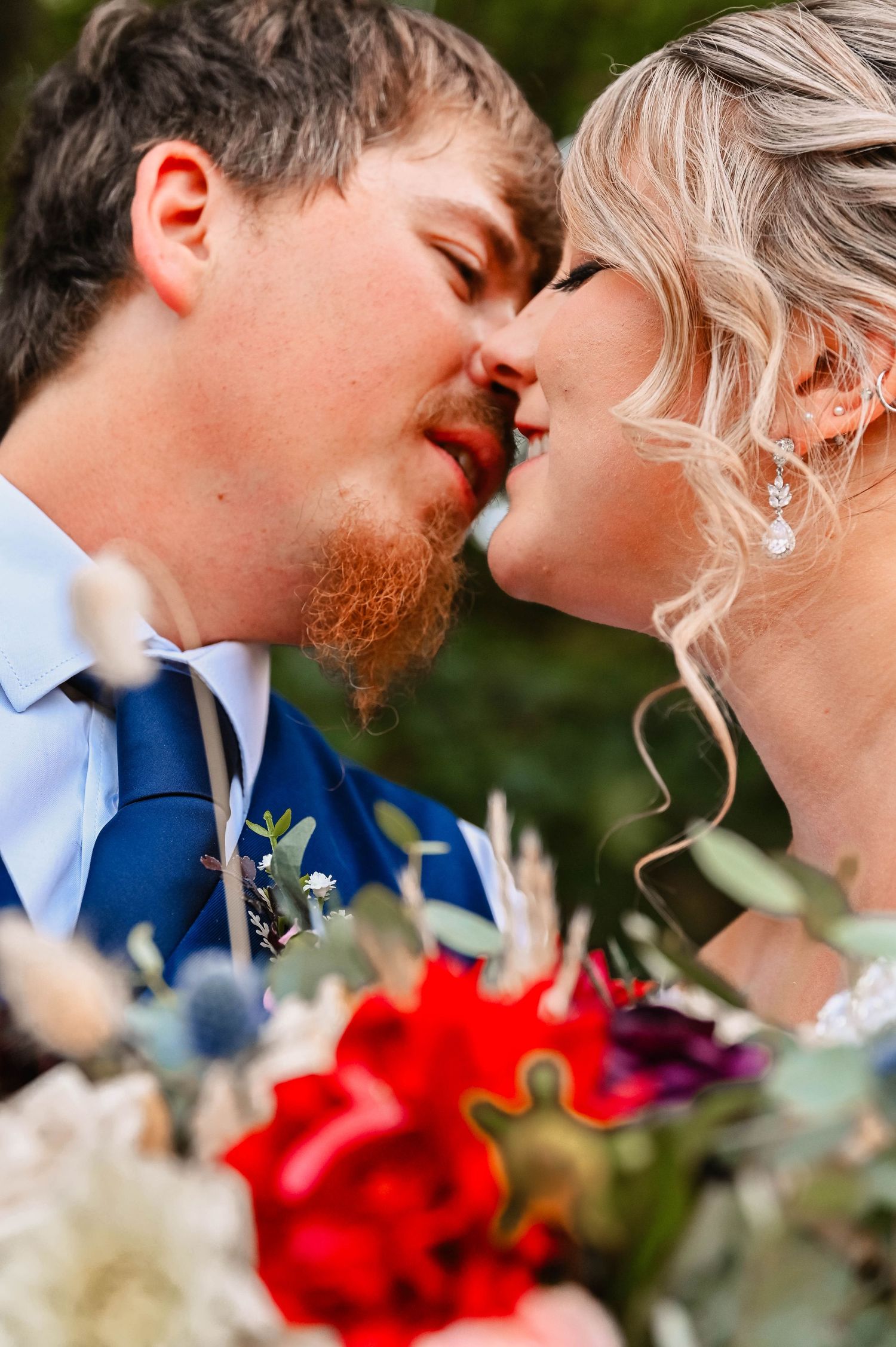 Romantic wedding moment captured among colorful floral bouquets.