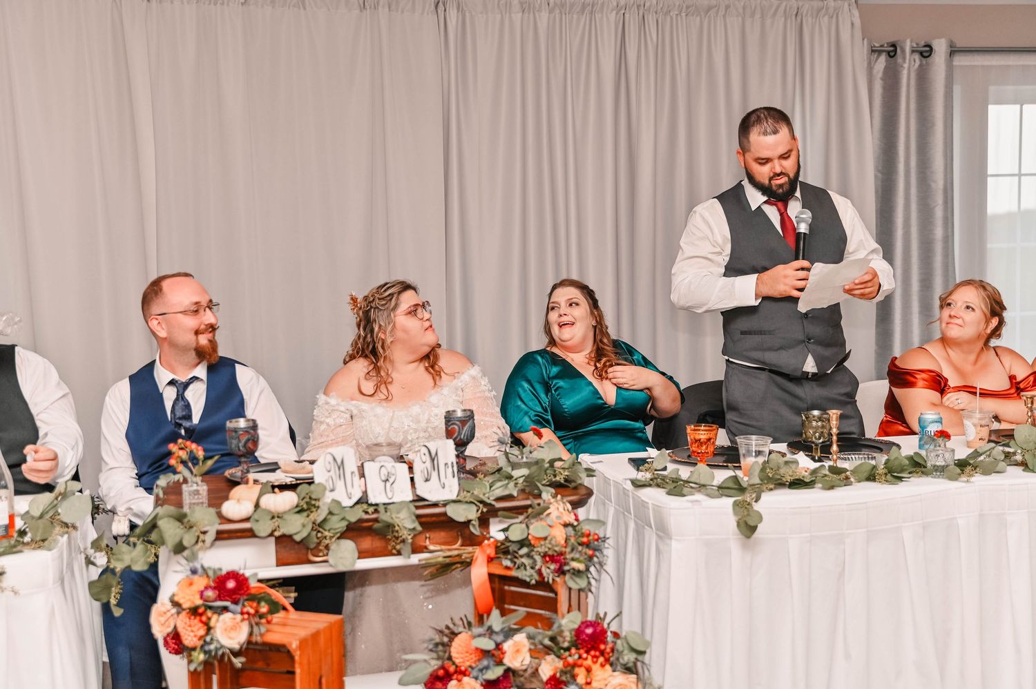 Wedding reception dining setup with white tablecloths and fall decor.