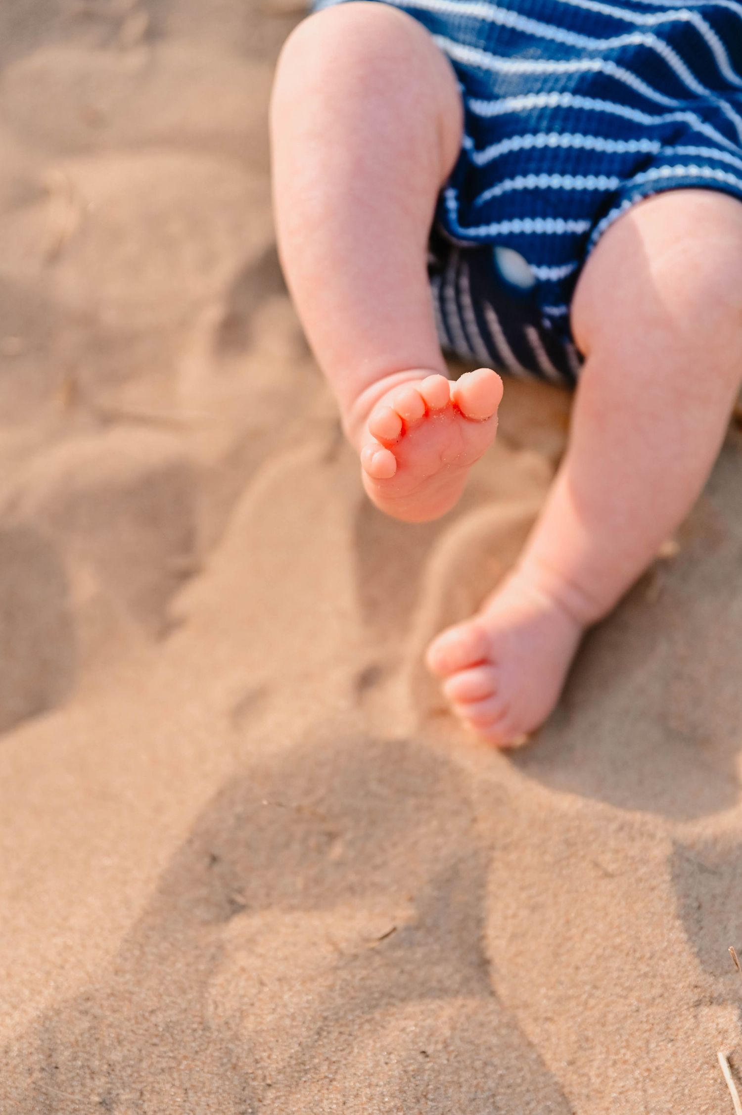 Close-up of baby's feet touching soft beach sand.