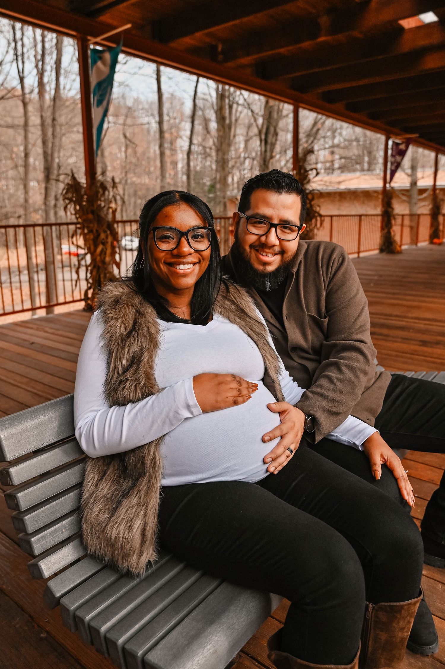 A couple sits close together on a wooden bench sharing tender moments.