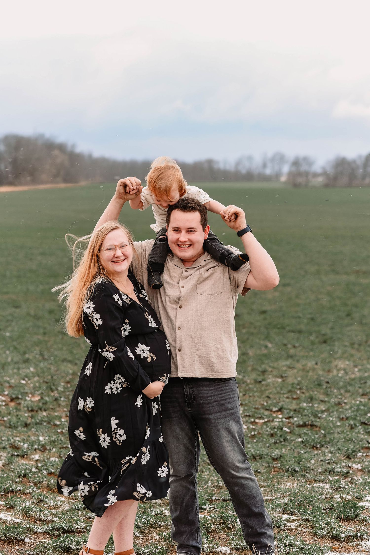 Family poses playfully in an open field during spring photo session.