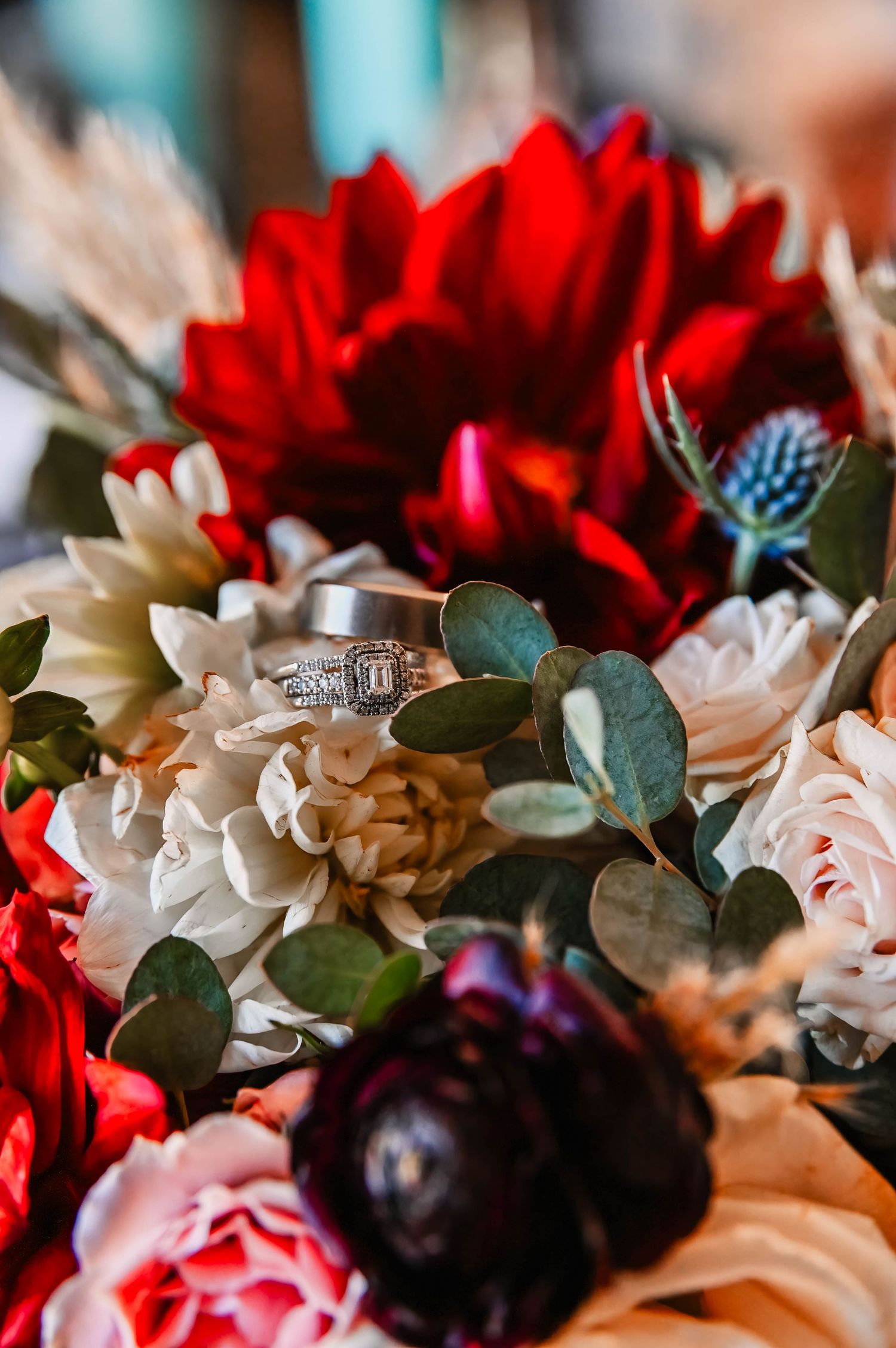 Close-up of red and white flowers with green foliage in a wedding bouquet arrangement.