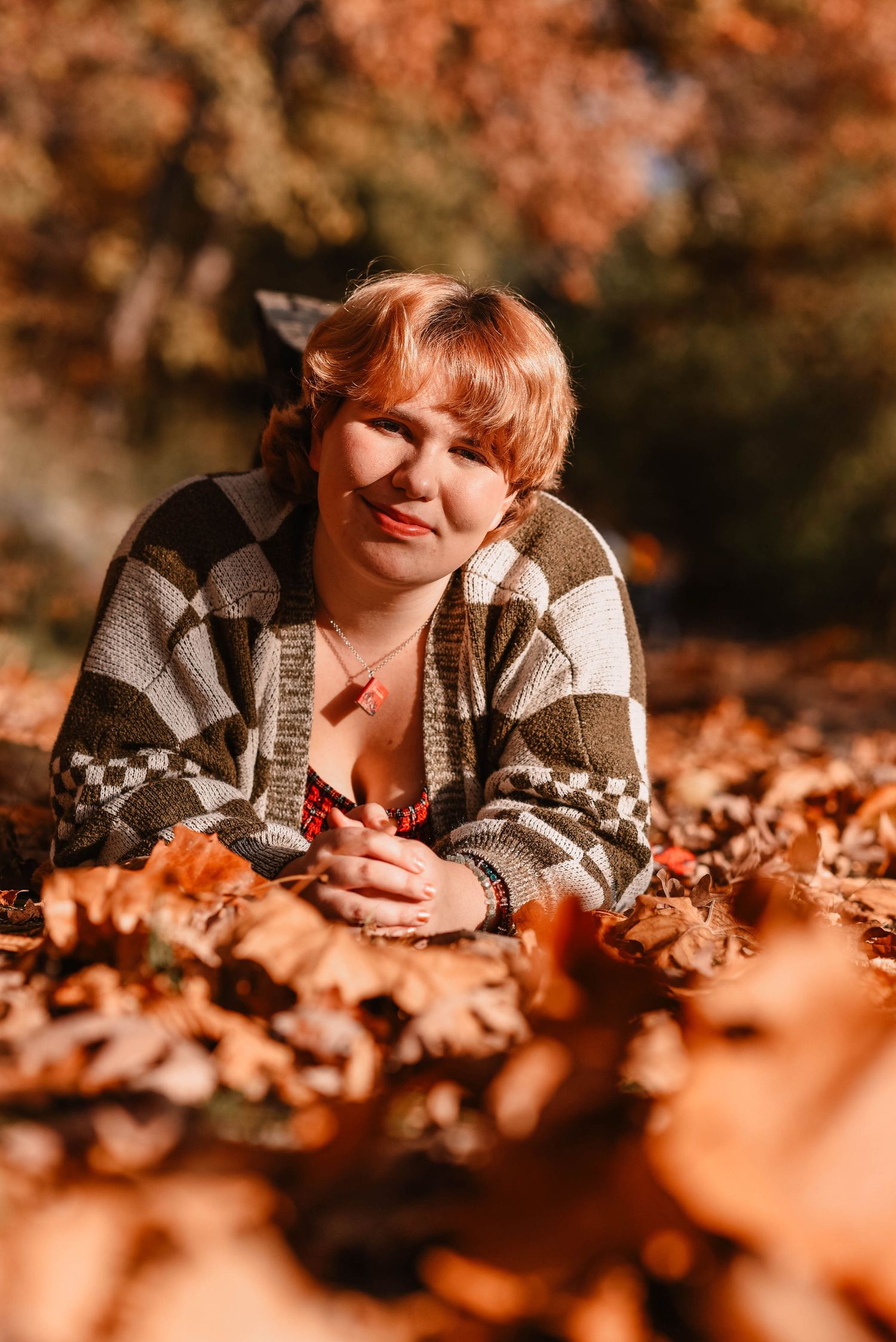Portrait in striped sweater surrounded by vibrant autumn foliage.