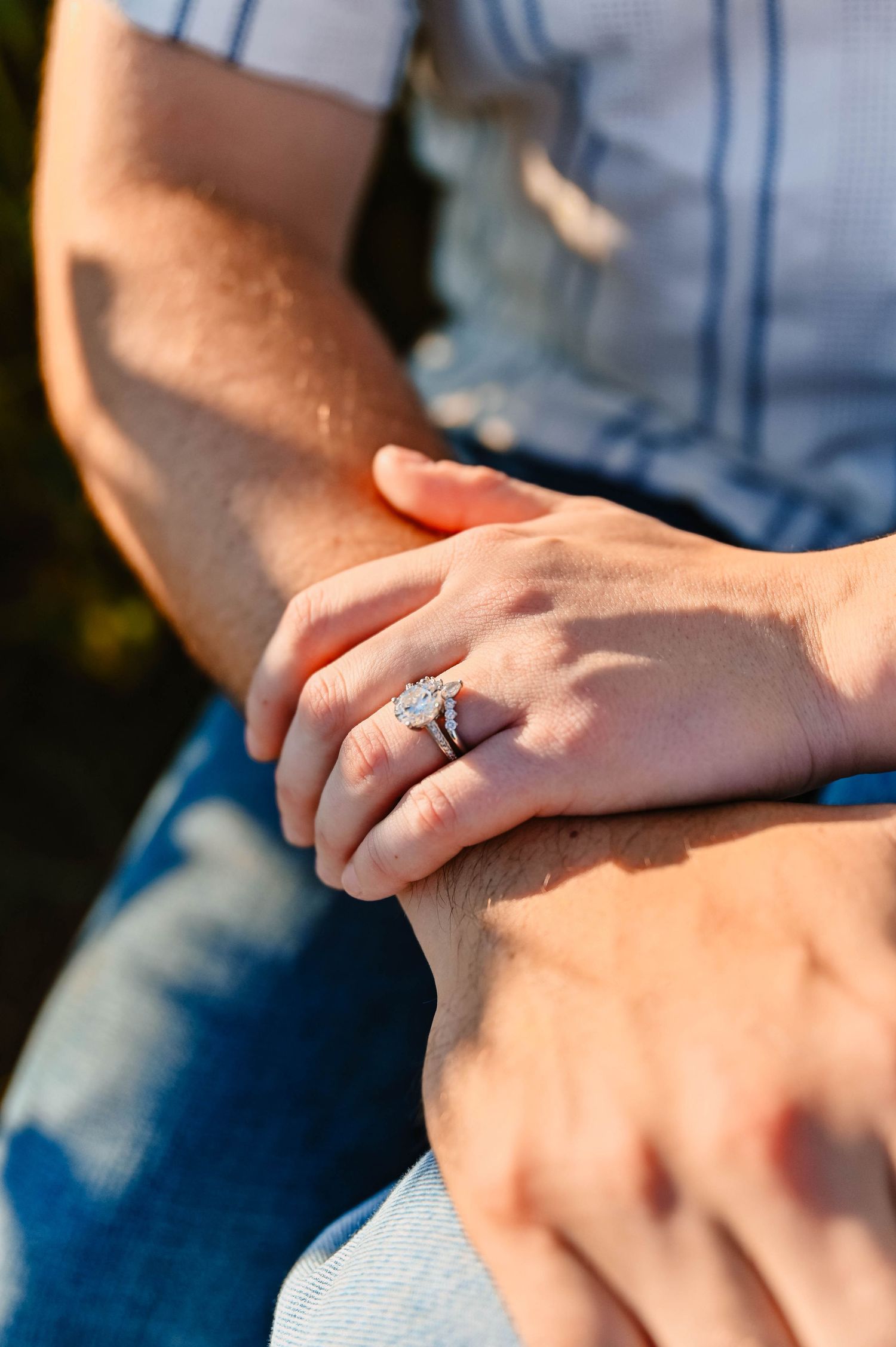 Close-up of hands showing engagement ring in natural sunlight.
