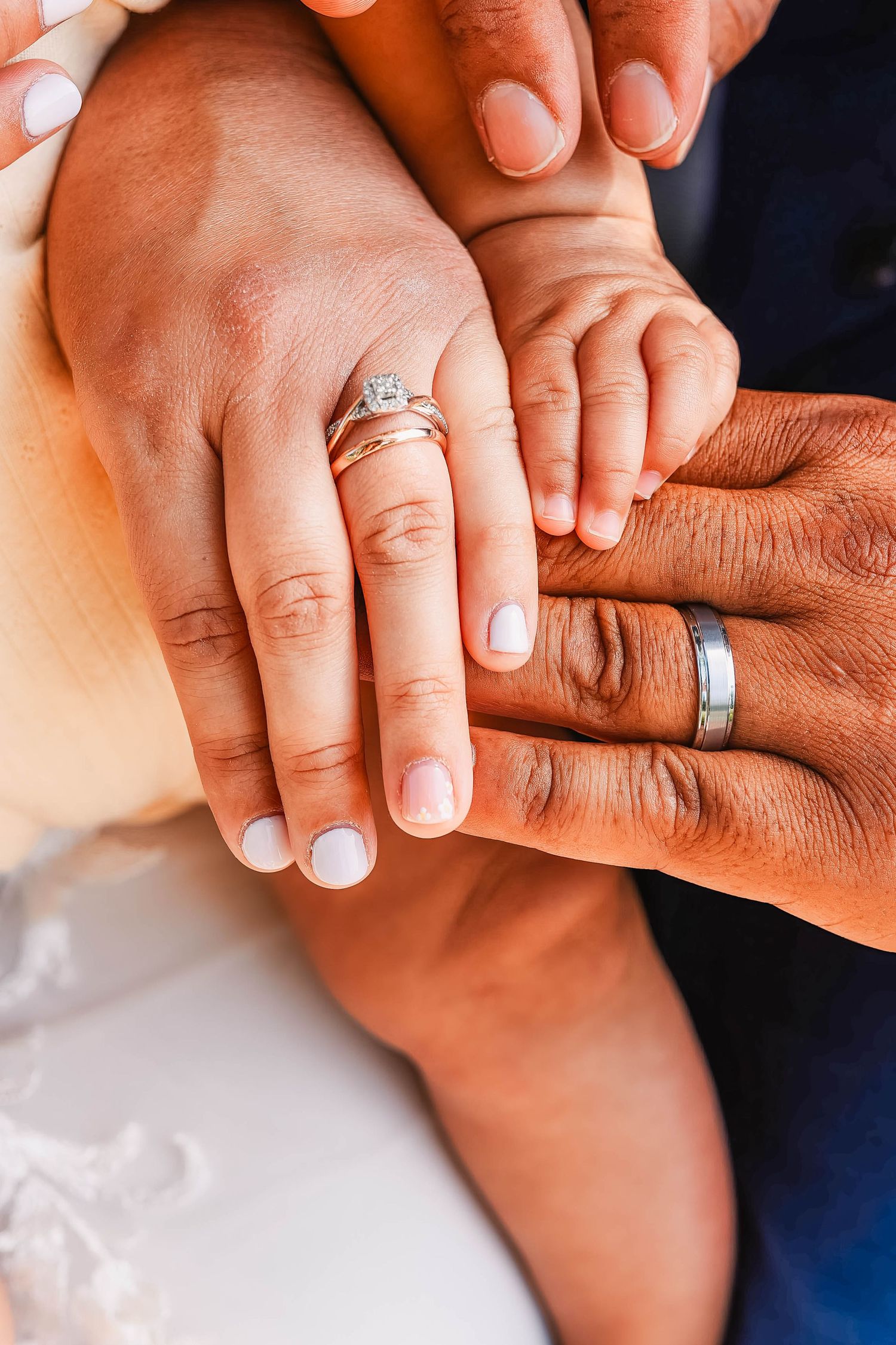 Close-up of newlyweds' hands showing wedding rings and manicured nails.