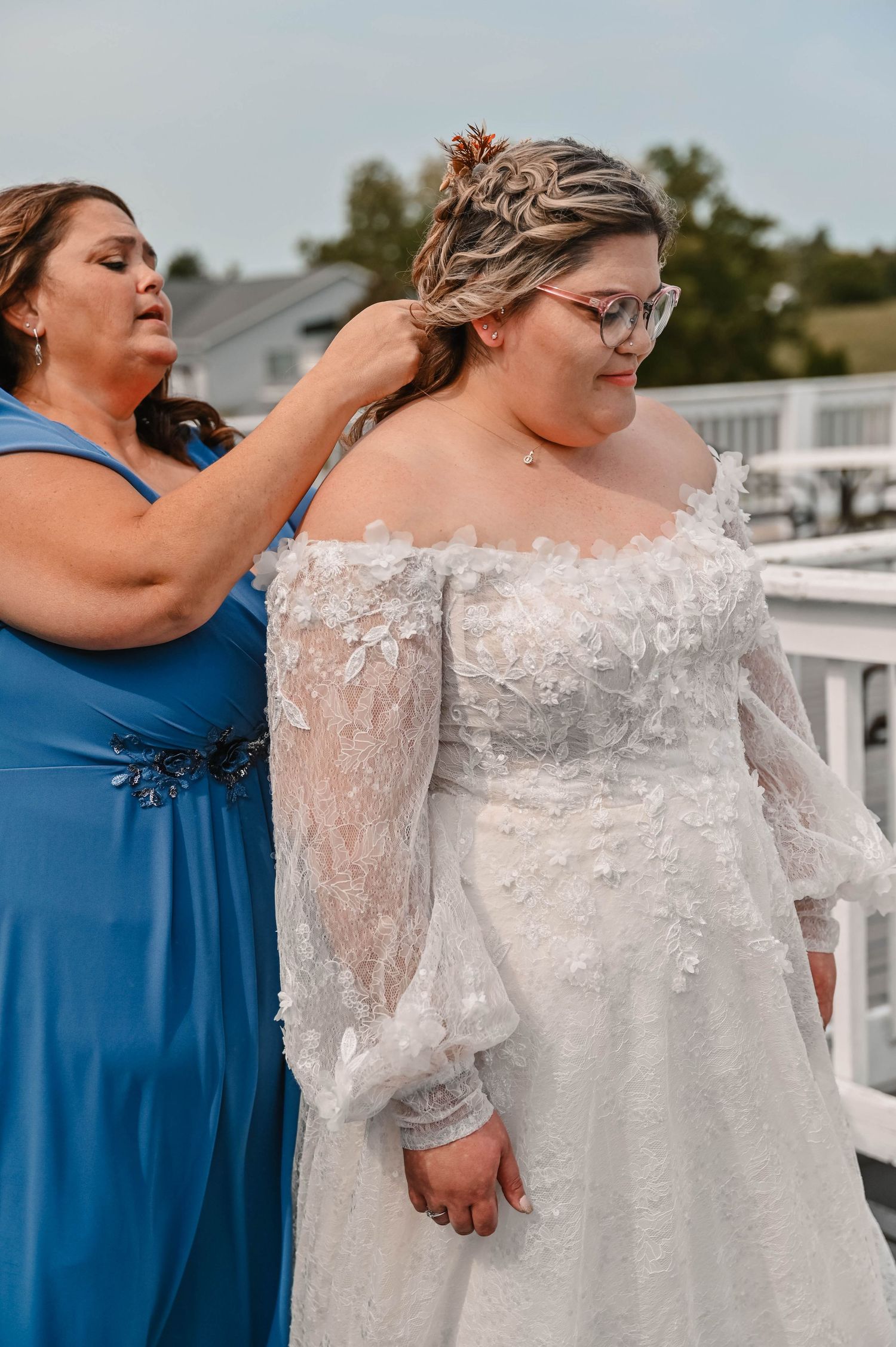 Bride in lace off-shoulder wedding dress with bridesmaids in blue dresses.