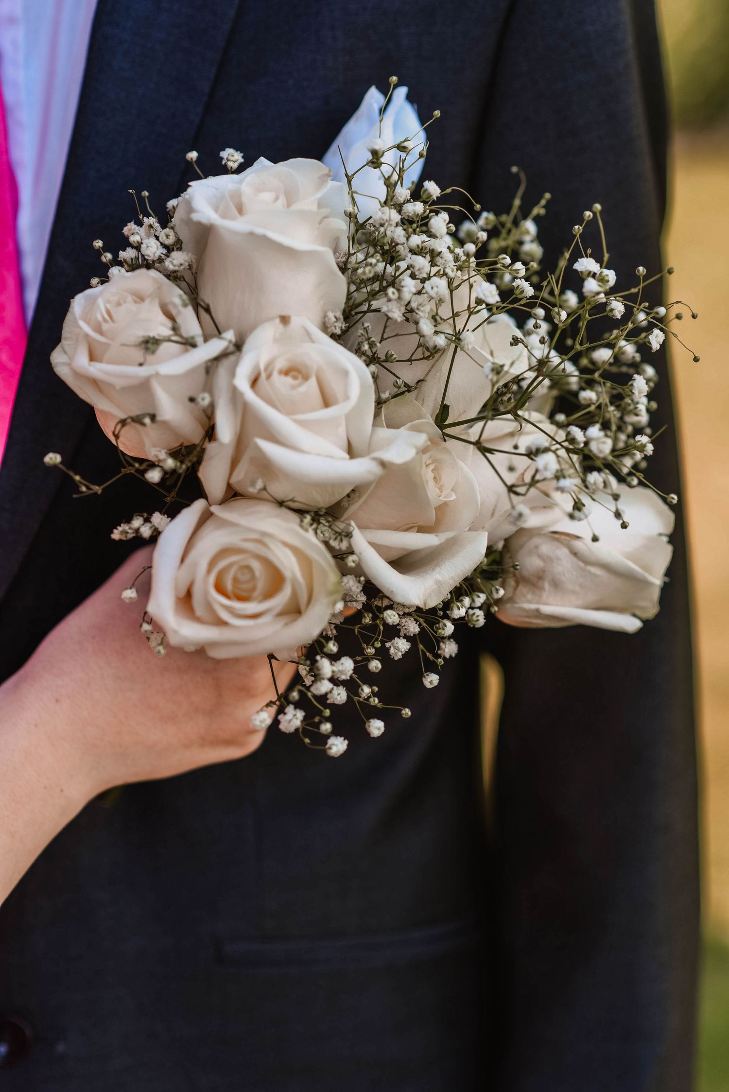 White rose and baby's breath corsage pinned to black formal suit.