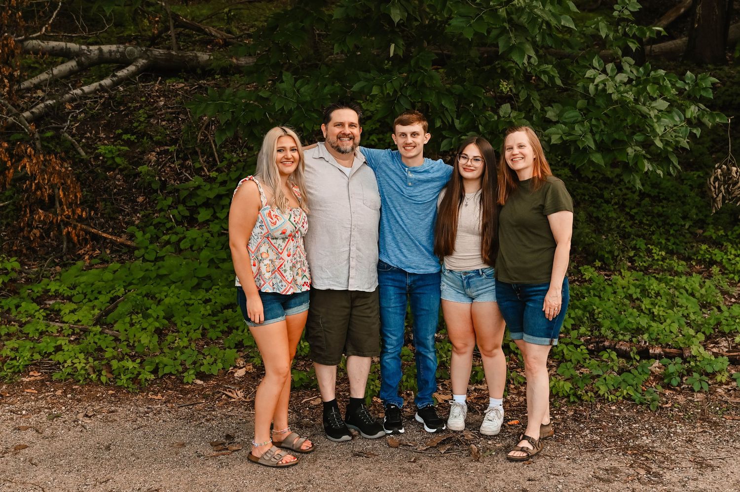 A casual group photo taken outdoors on a dirt path with trees in the background.