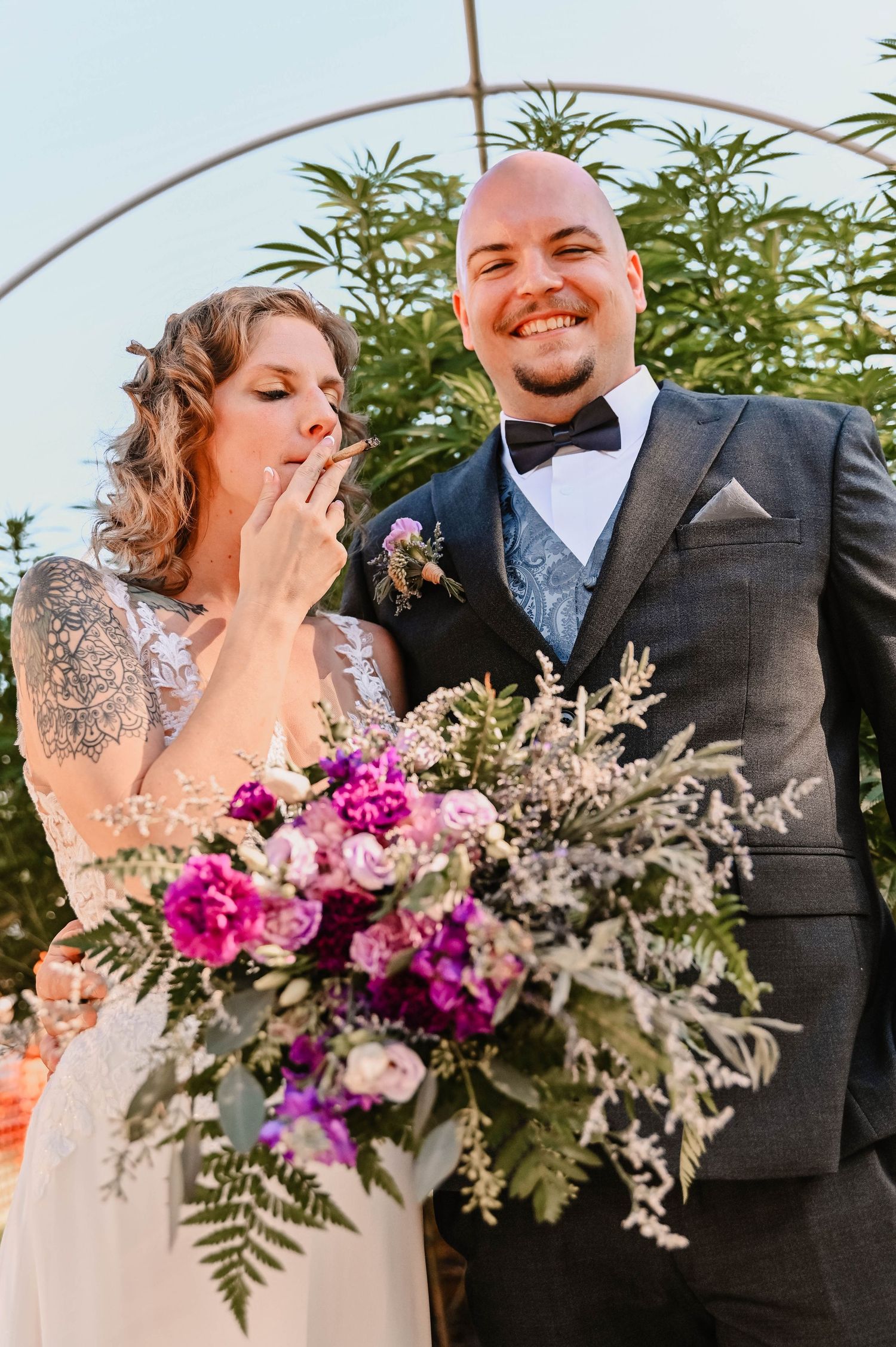Couple laughing together during outdoor wedding ceremony with vibrant floral arrangements.