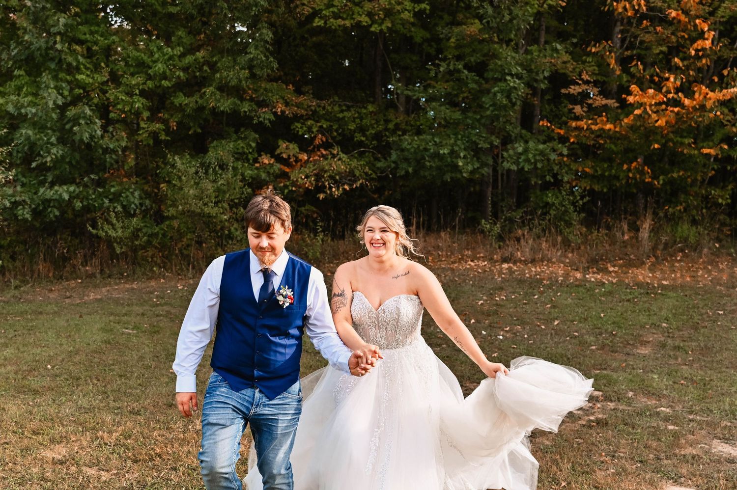 Couple walking together in a wooded outdoor setting during autumn.