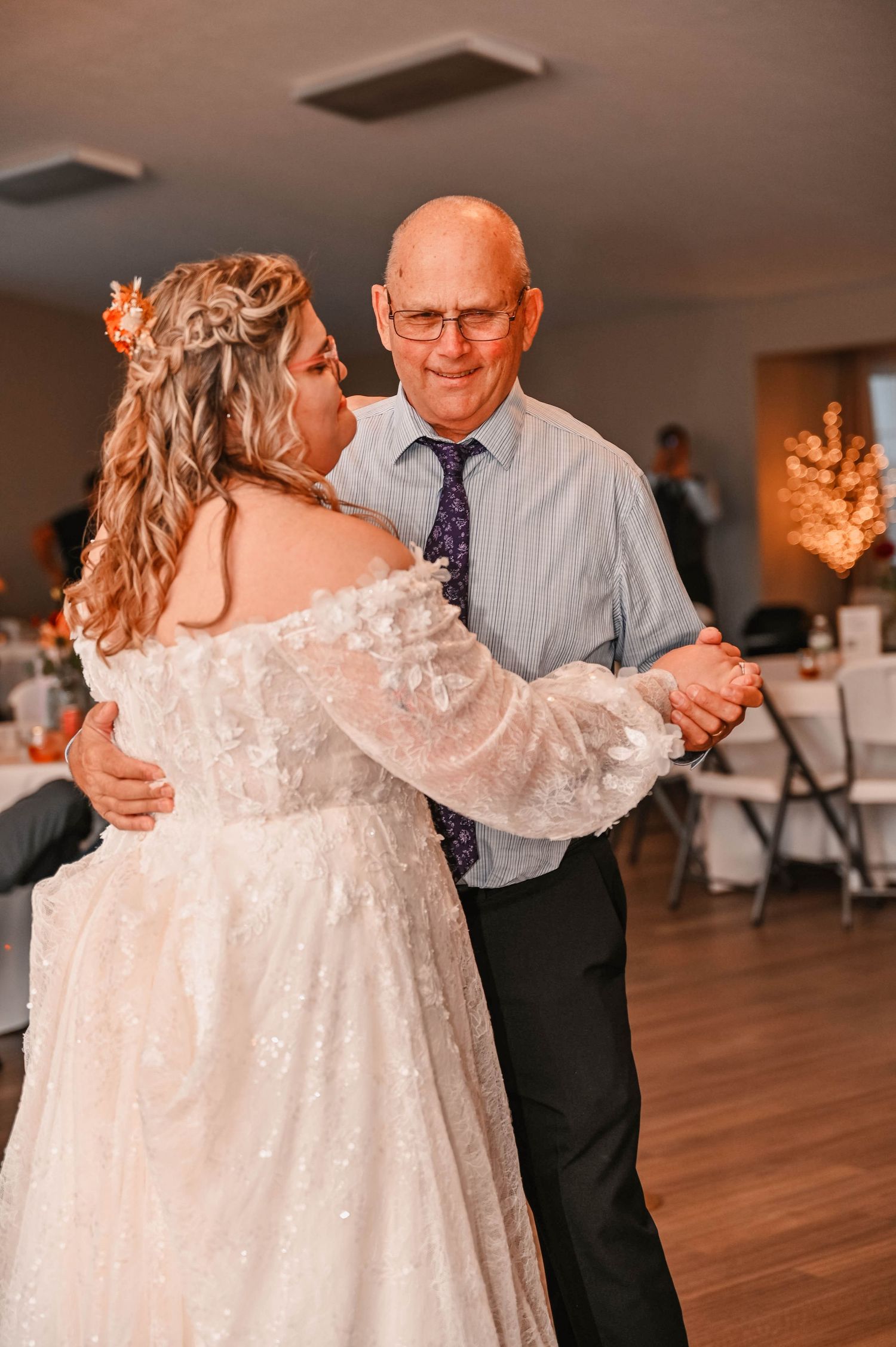 Dancing on wooden floor at wedding reception in white lace dress.
