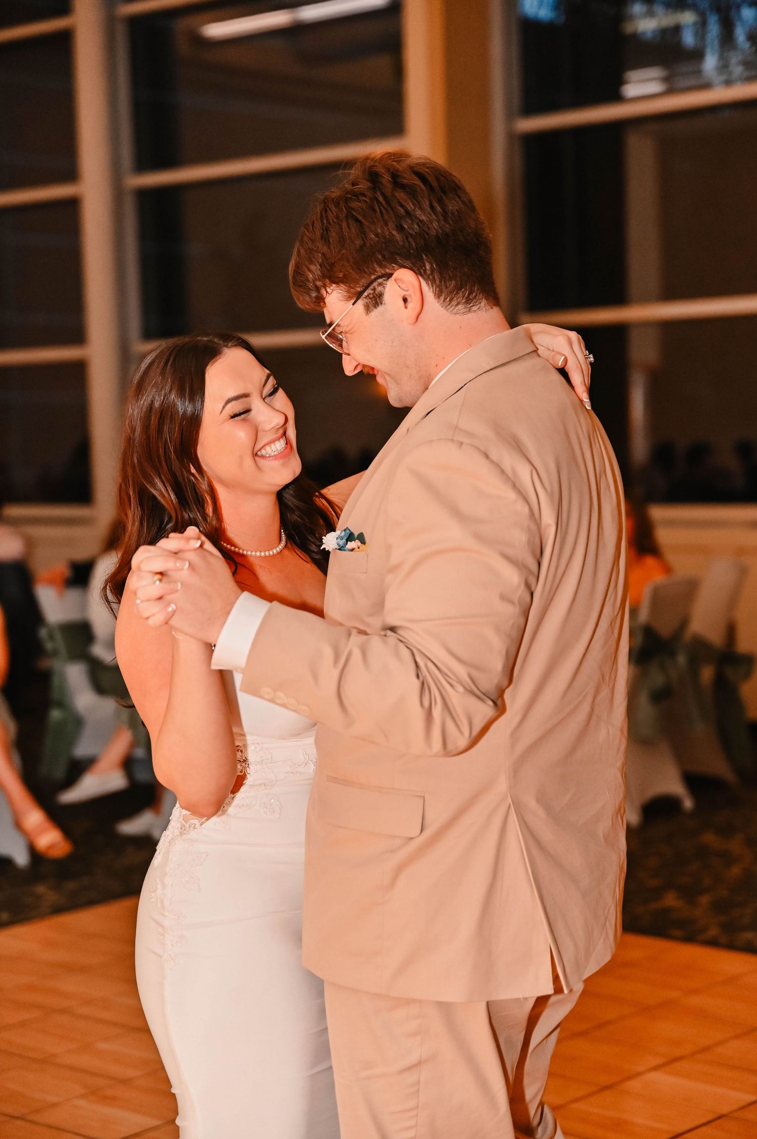Couple shares an intimate dance moment in warm lighting at wedding reception.
