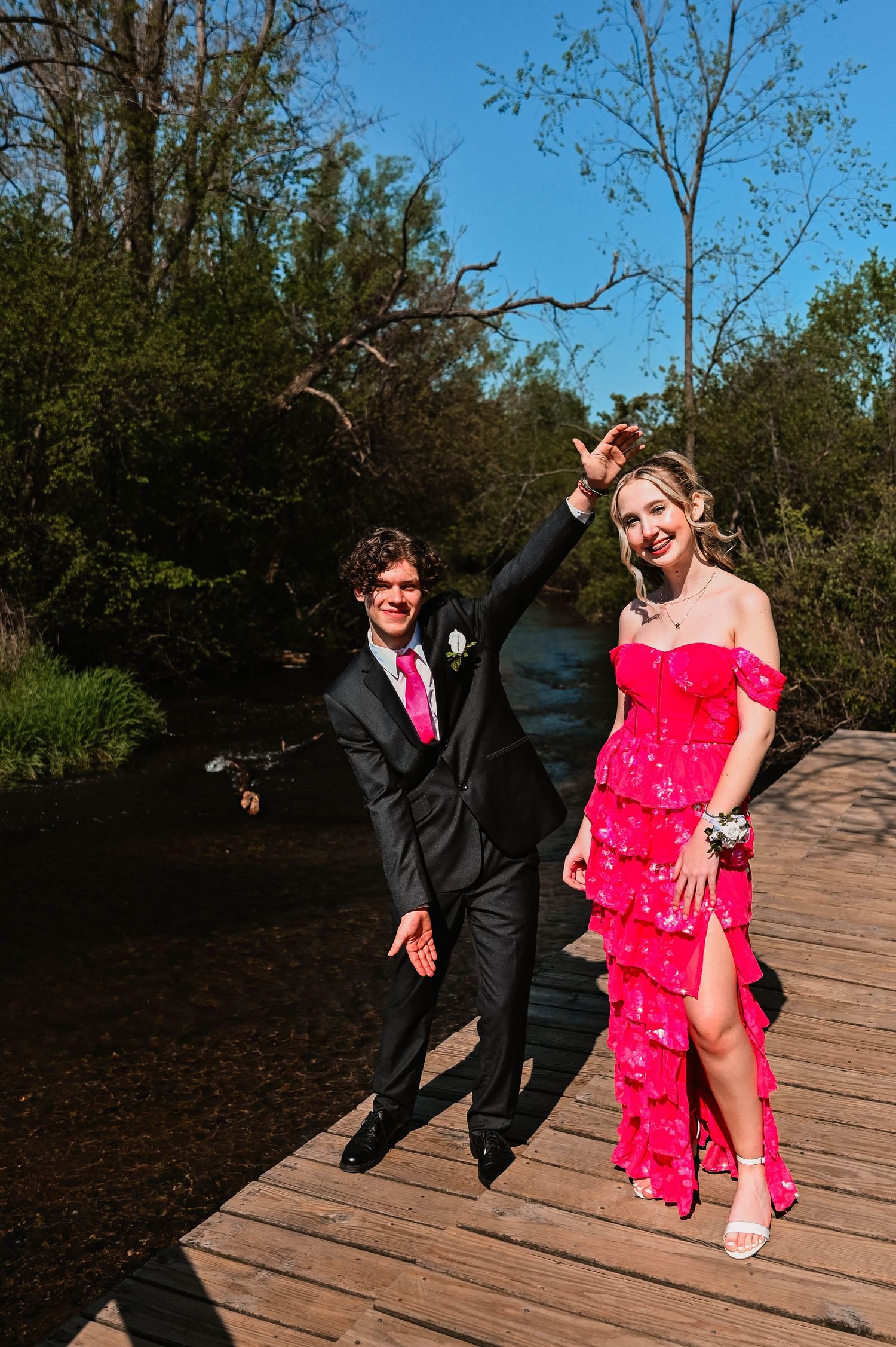 Couple in formal wear having fun and dancing on wooden deck outdoors.