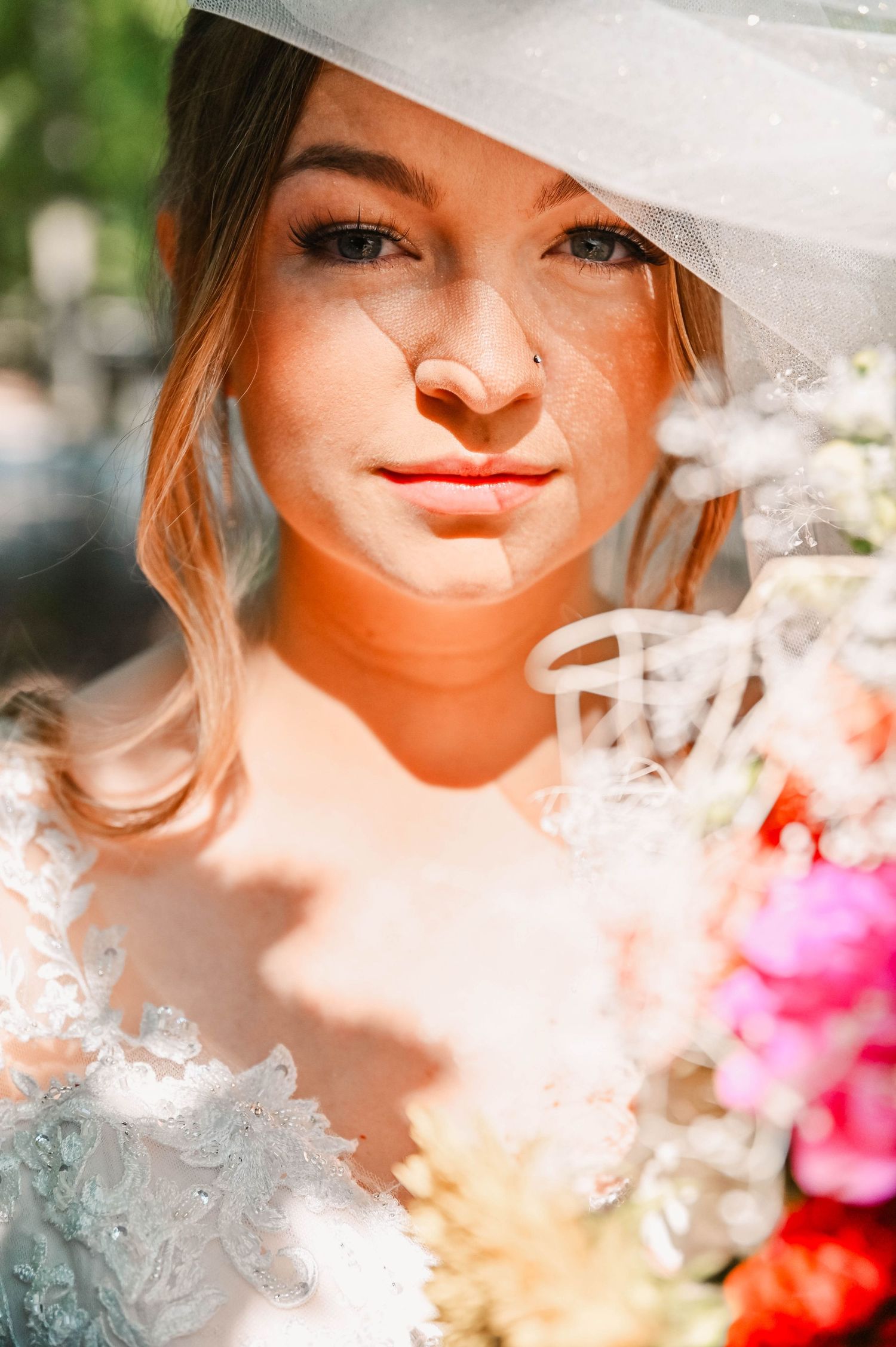 Artistic close-up portrait through soft focus flowers and sunlight.