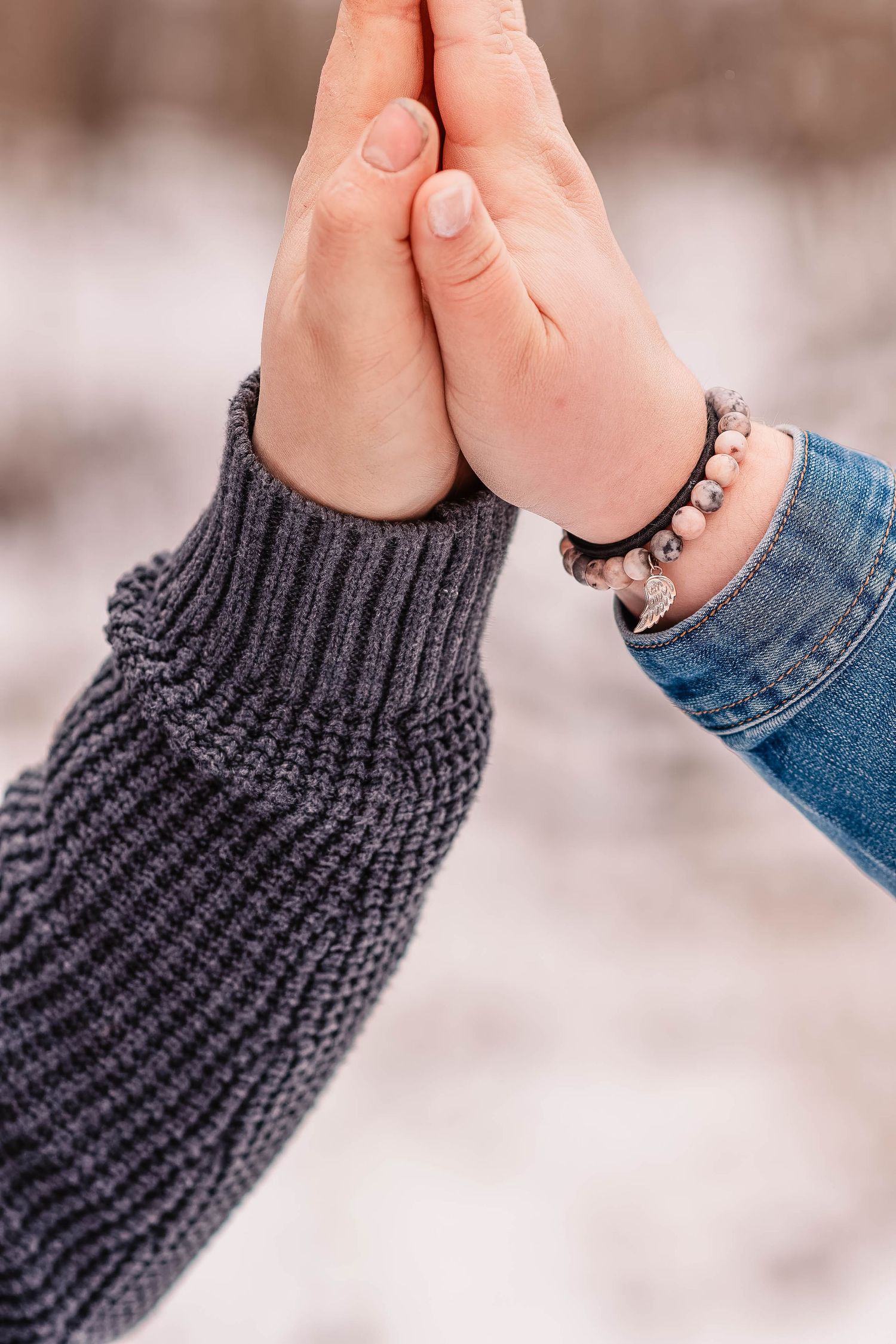 Close-up of hands touching against knit sweater sleeve in winter setting.