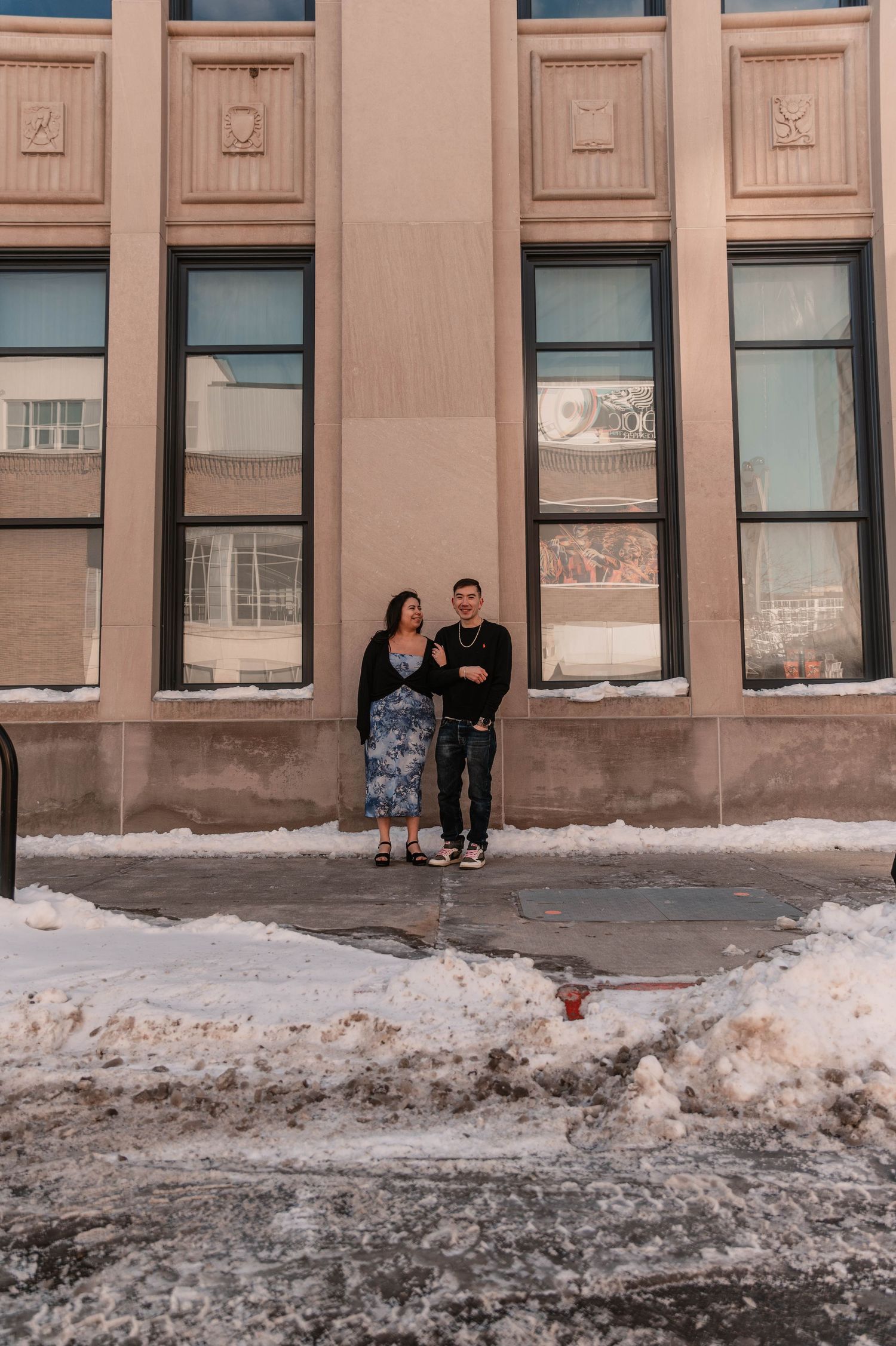 Winter urban scene with snow piles along building exterior.