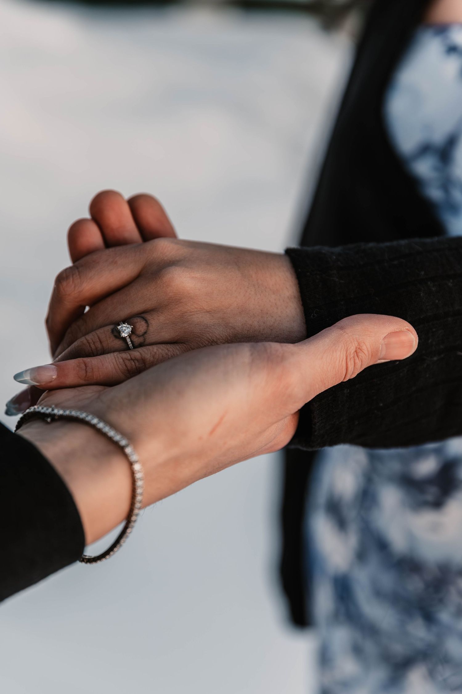Close-up sequence of hands with engagement ring against snowy background.