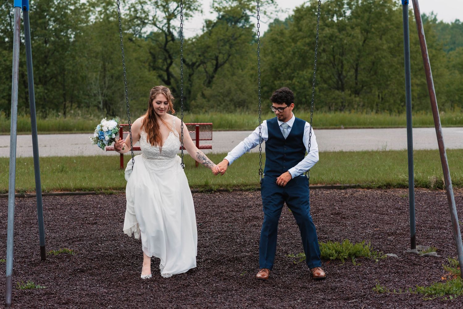 Playful wedding photos taken at a playground with swings.