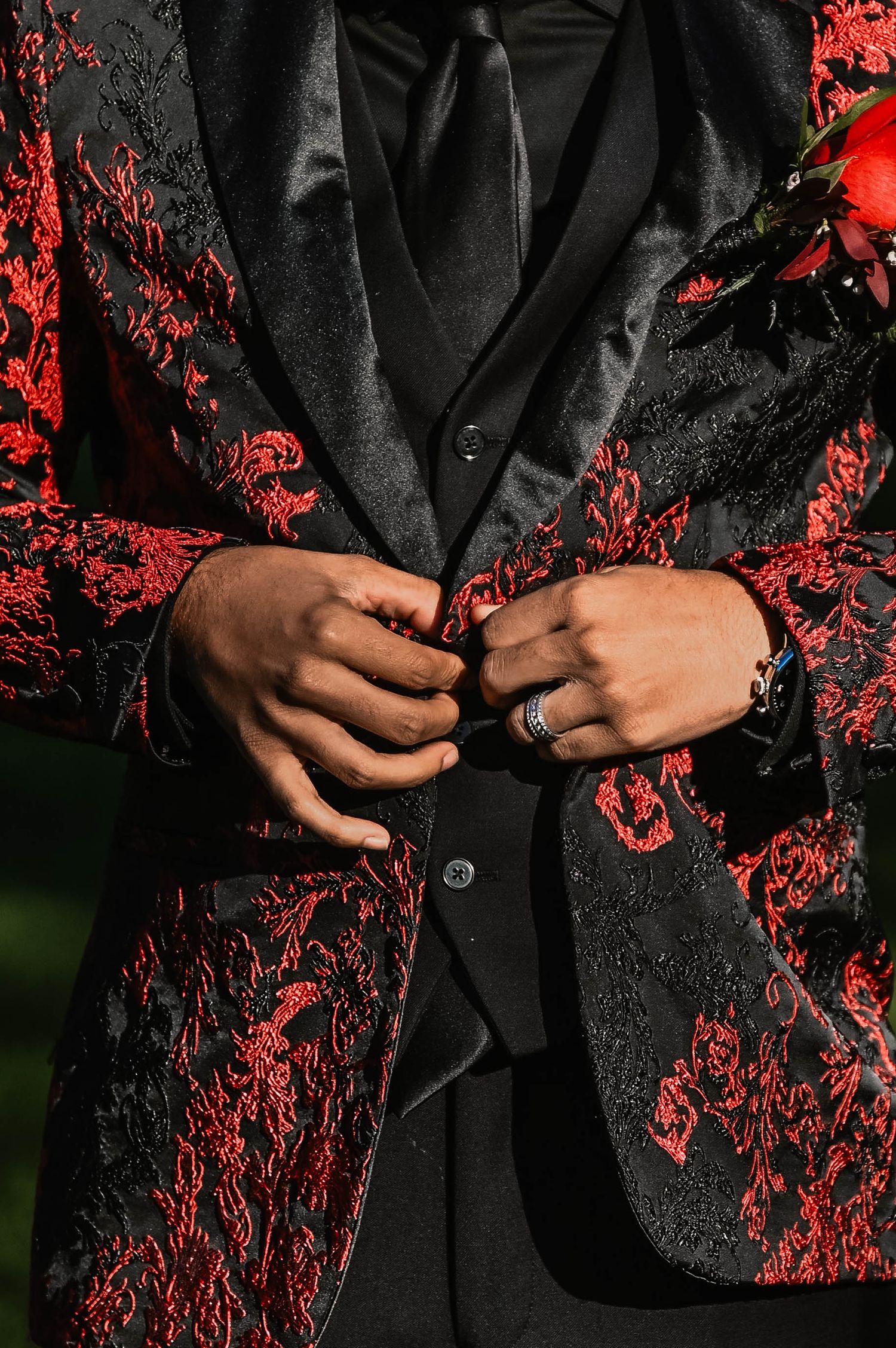 Detail shots of a black and red floral patterned suit jacket with hands adjusting buttons.