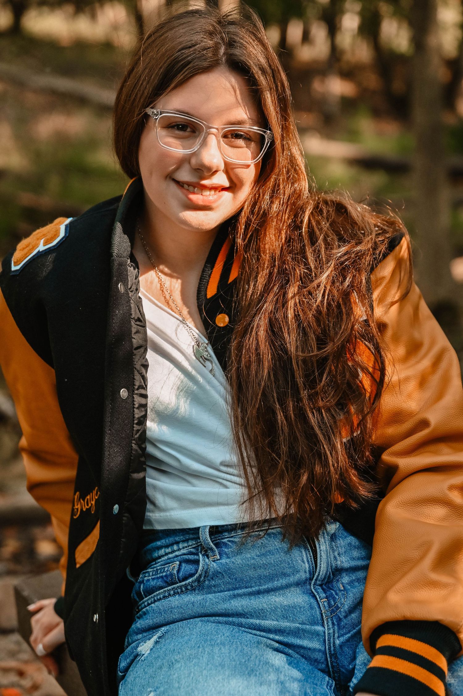 Casual portrait series featuring a black and orange varsity jacket with denim in natural lighting.