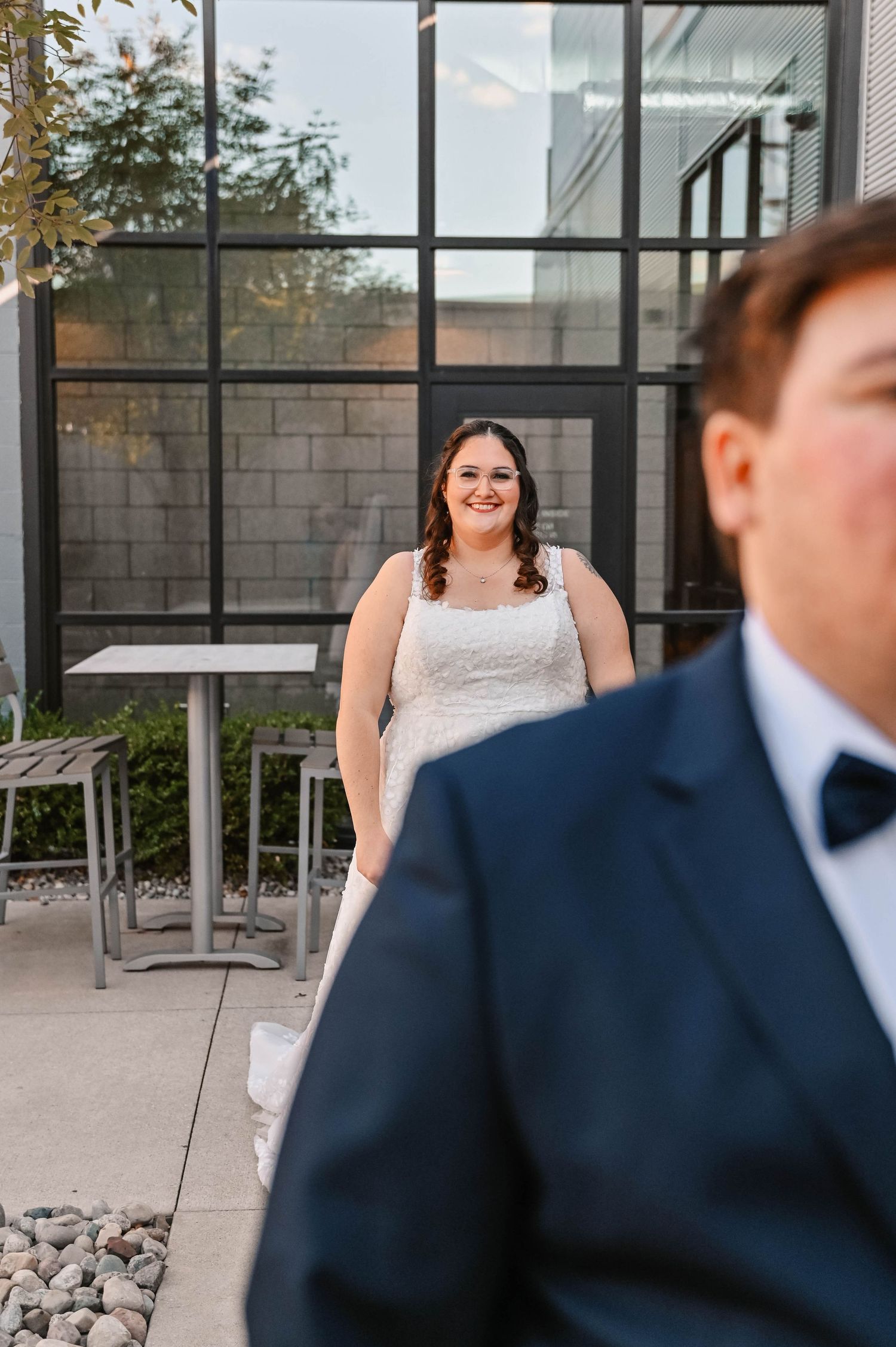 A first look wedding moment captured outside a modern building with glass windows.